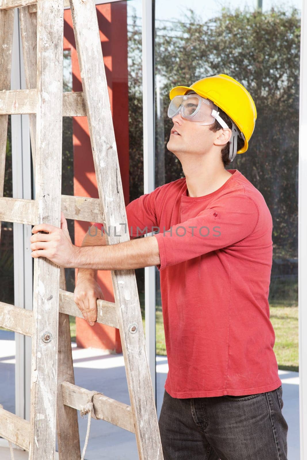 Architect wearing helmet and eyegear and holding ladder