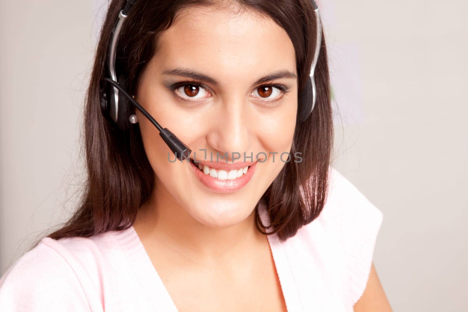 A female receptionist smiling at the viewer talking on the phone