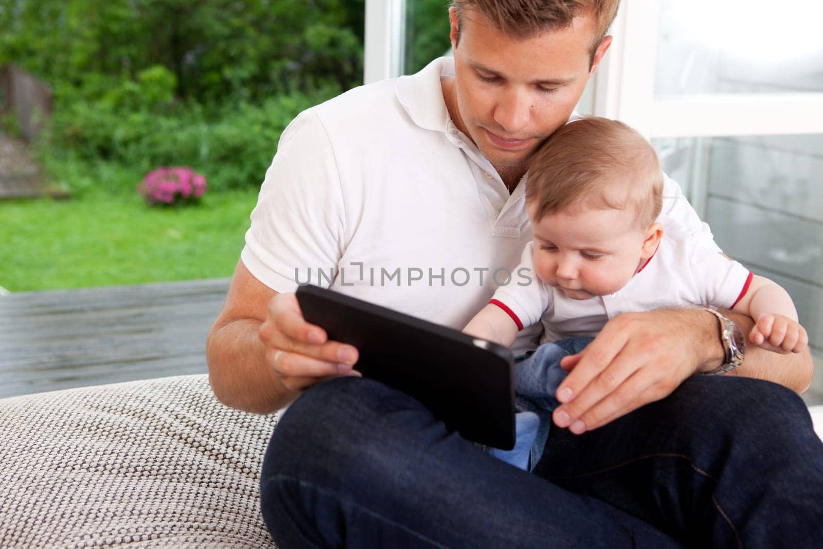 A father and son using a digital tablet in a home interior