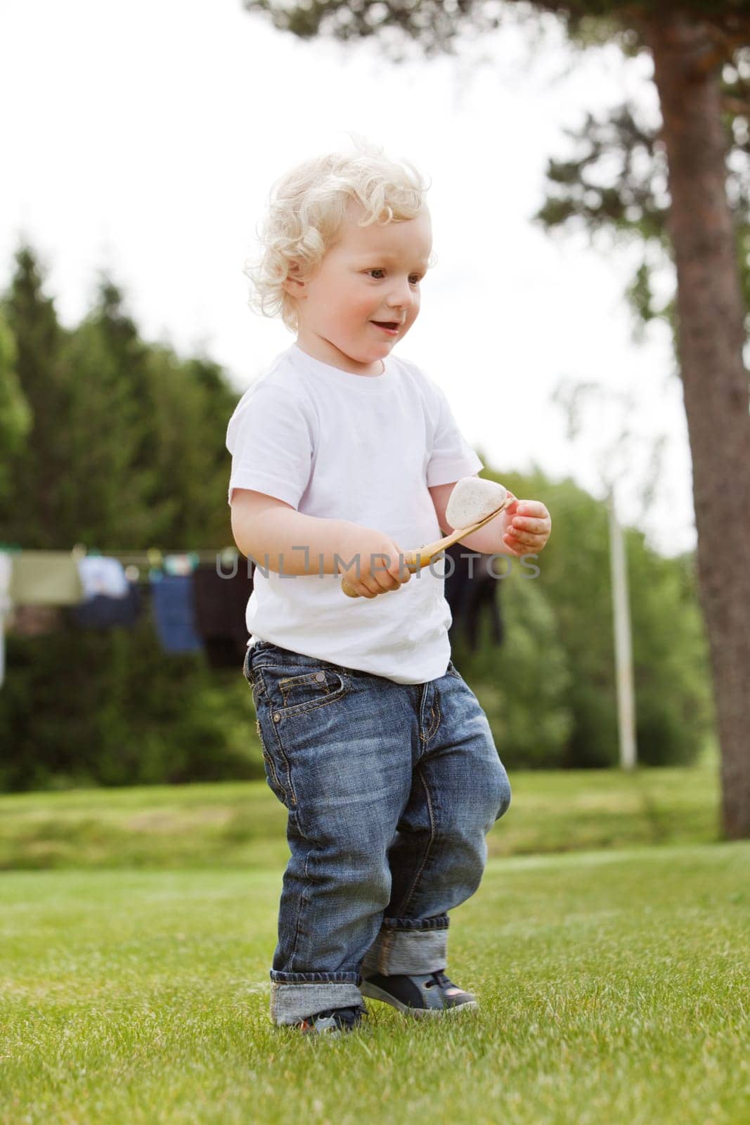 Full length of little boy holding gardening tool in garden