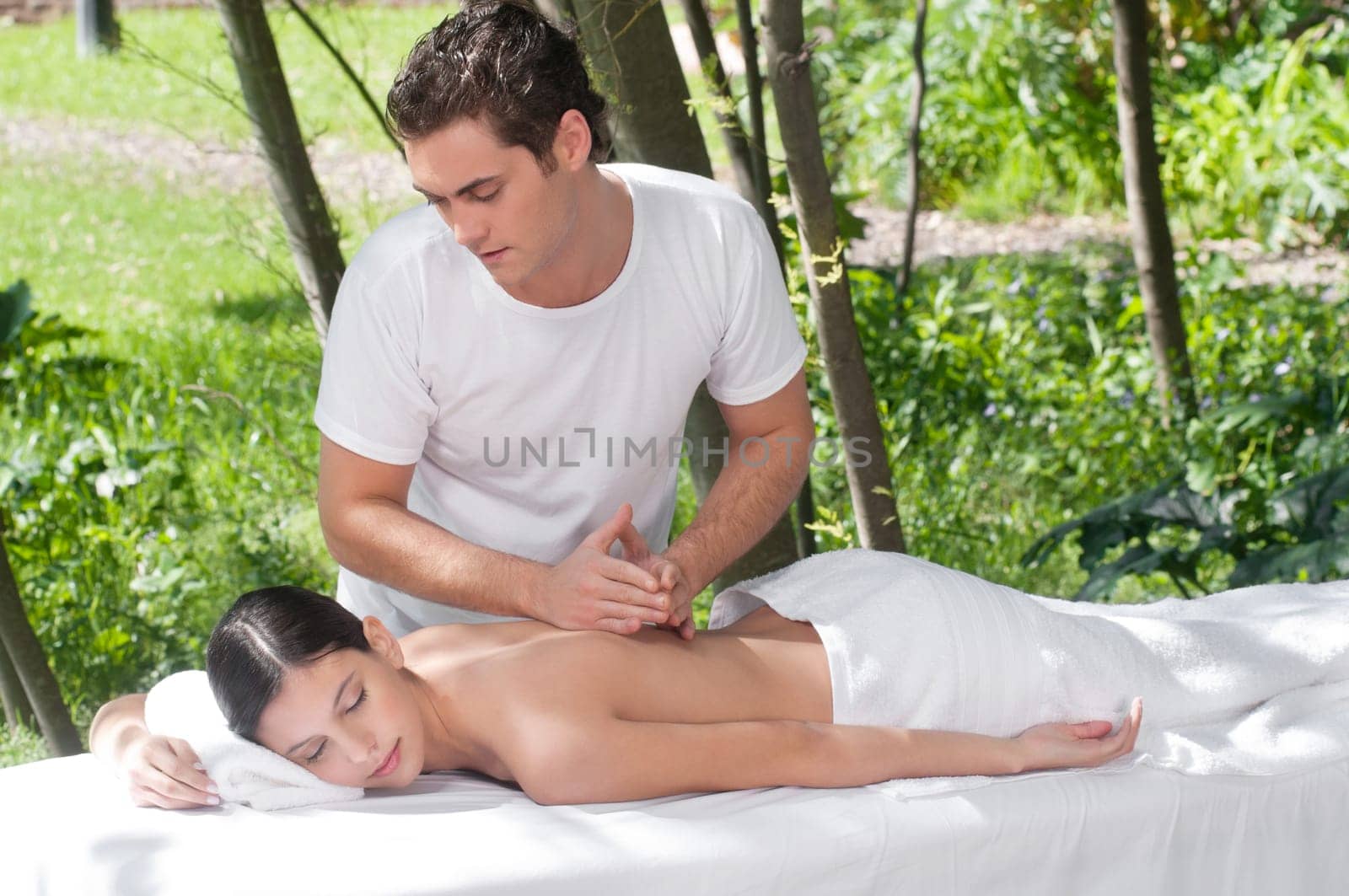 Woman receiving massage outdoors from professional masseuse