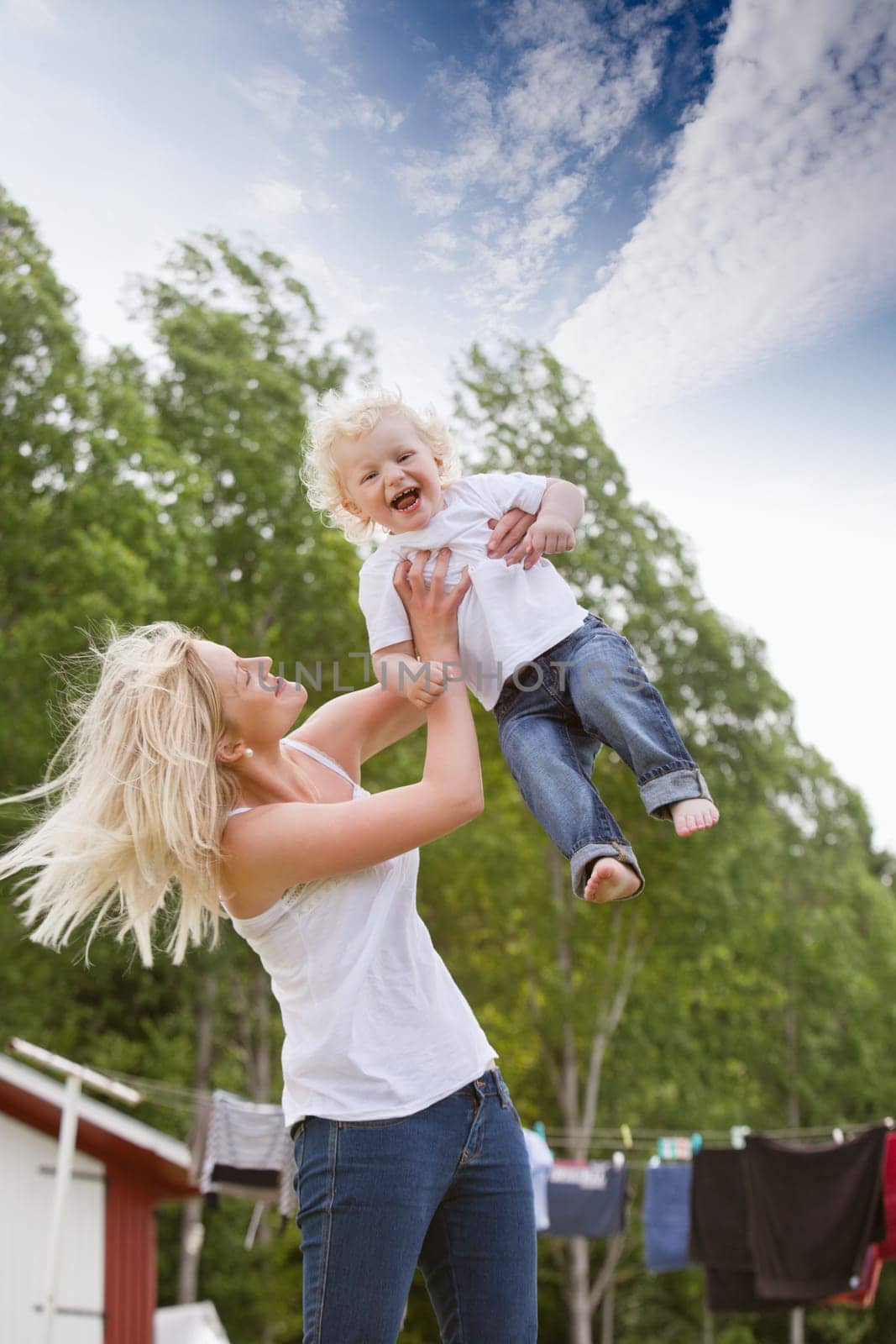Cheerful young mother holding her baby boy up