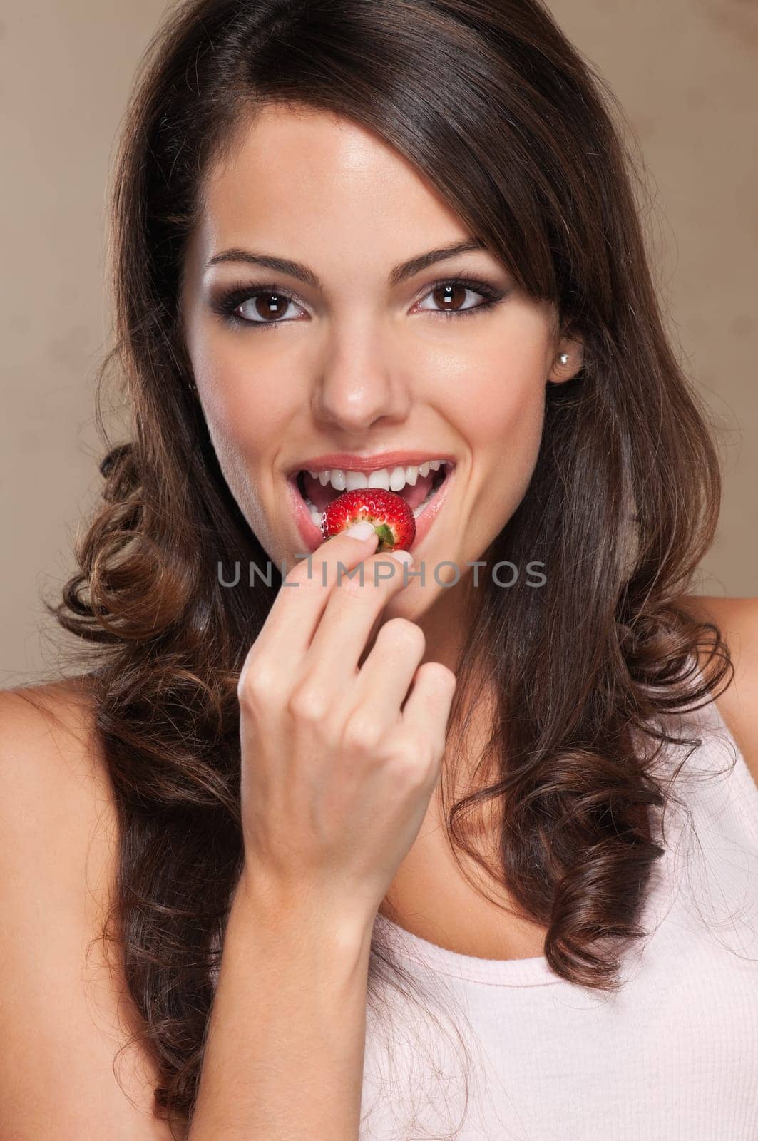 Close-up portrait of a cute female eating a fresh strawberry