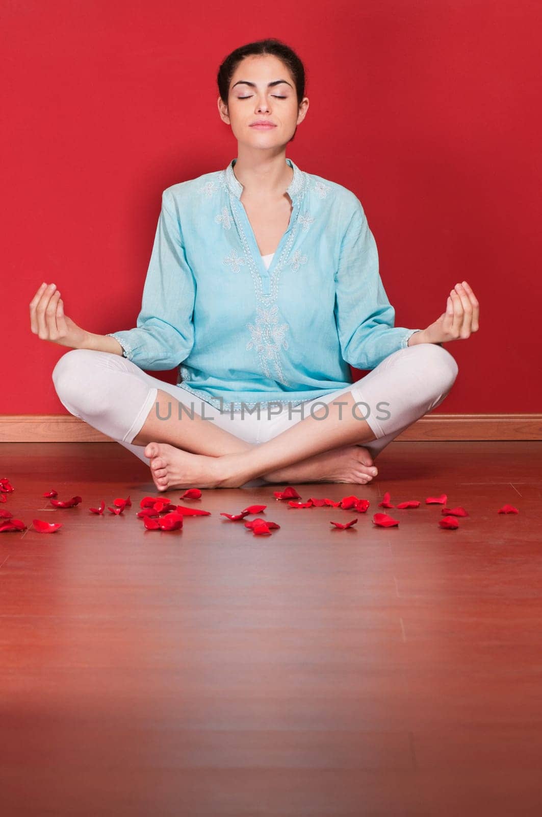 Female practicing yoga in the lotus position against colored background