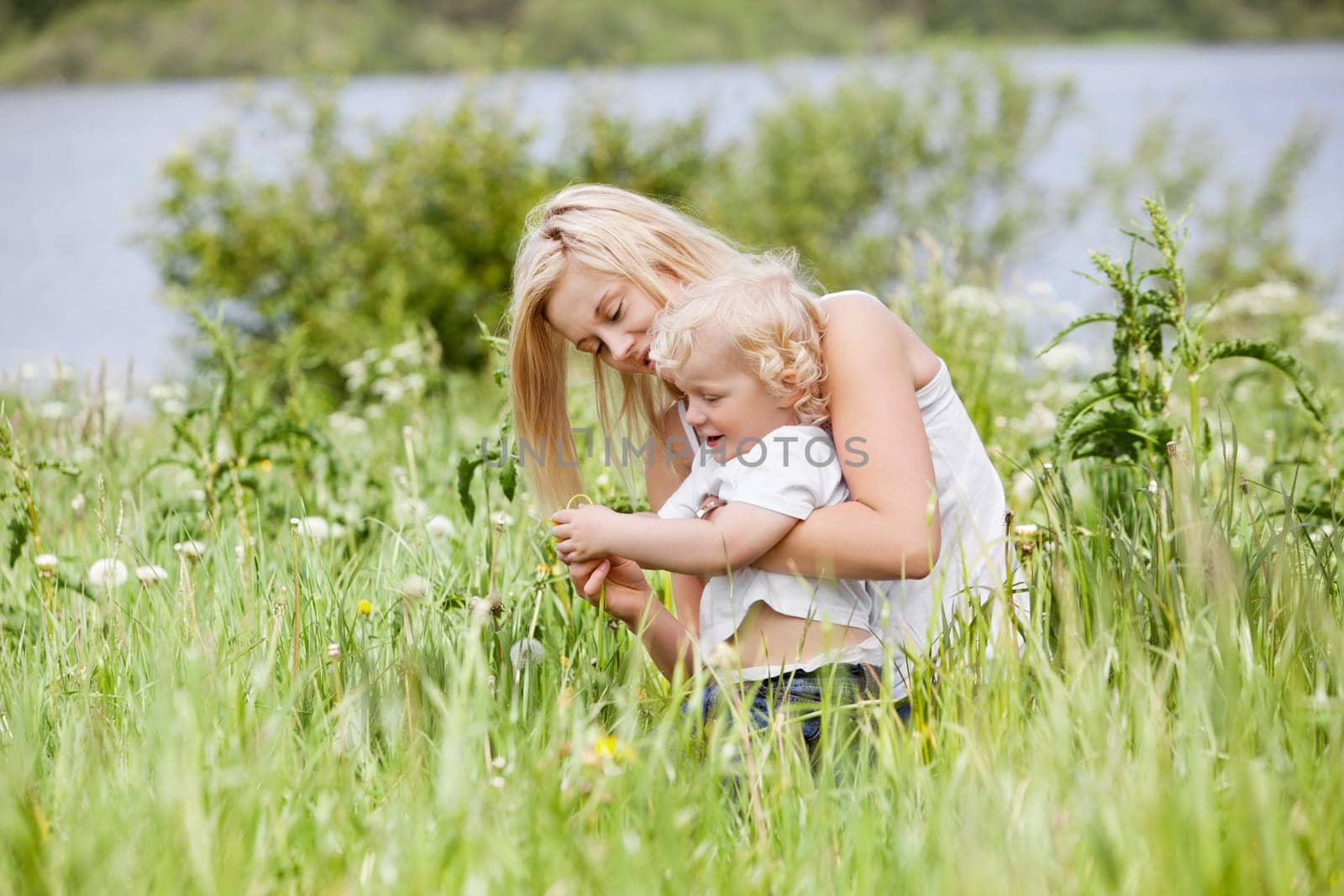 Beautiful young mother spending her time with her little son in grass