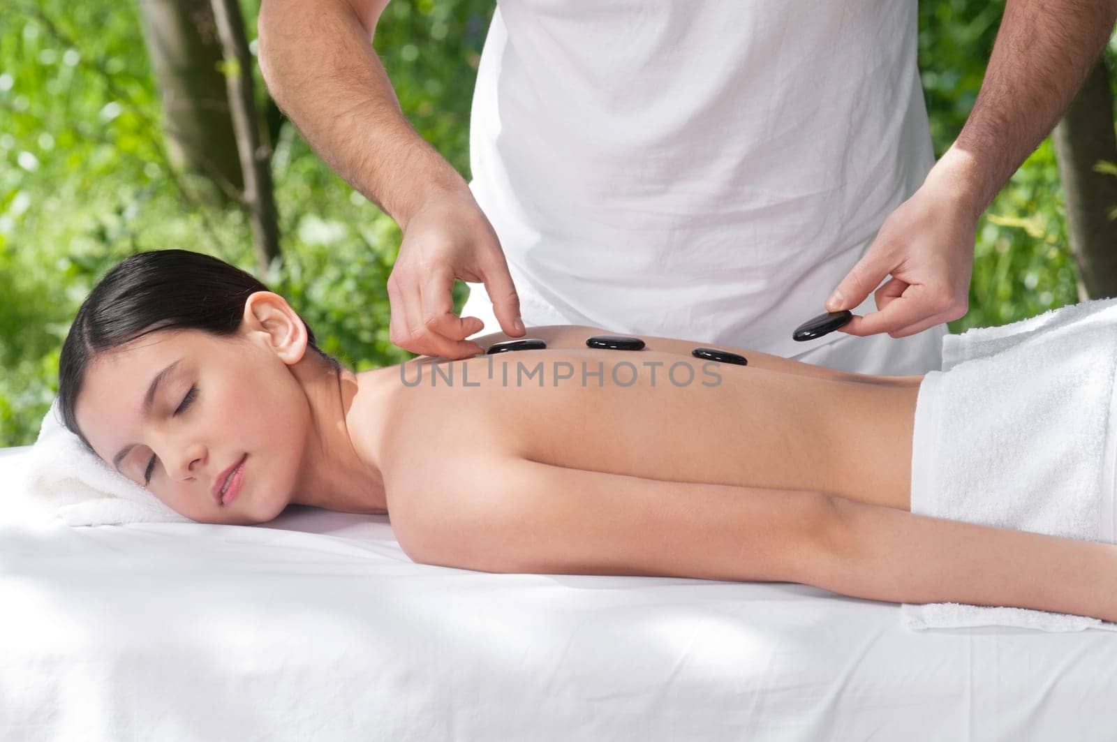 Young woman getting a hot stone massage at spa salon