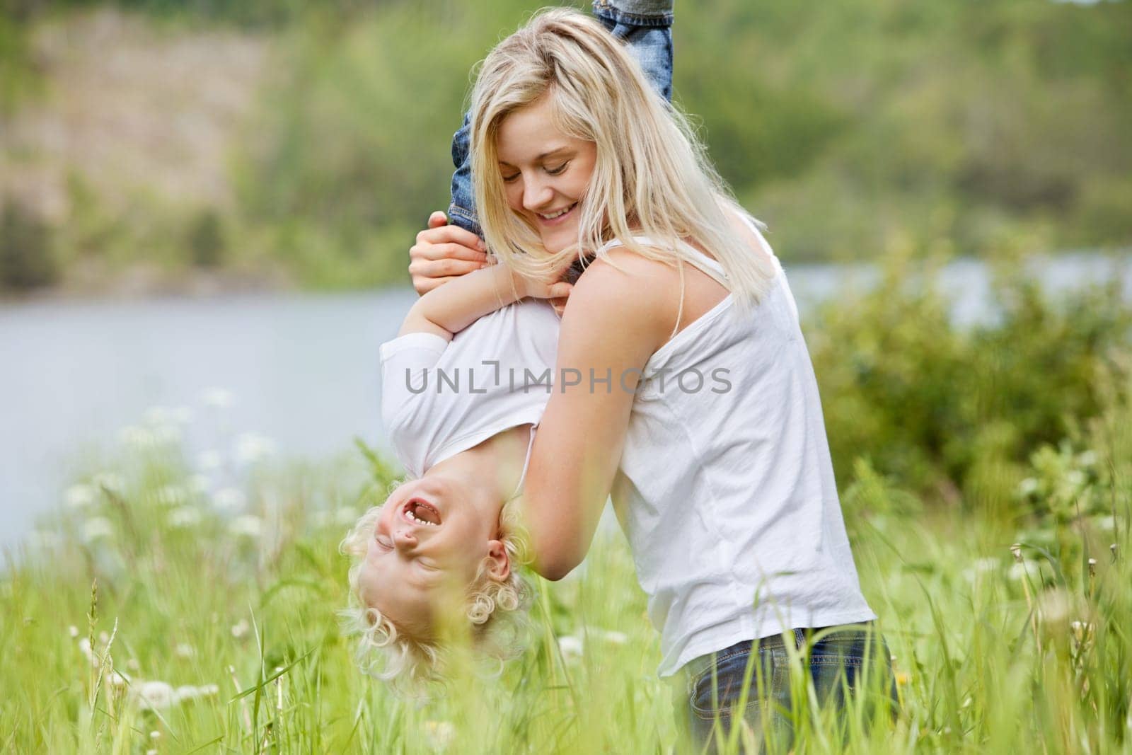 Playful woman in park playing with her laughing son
