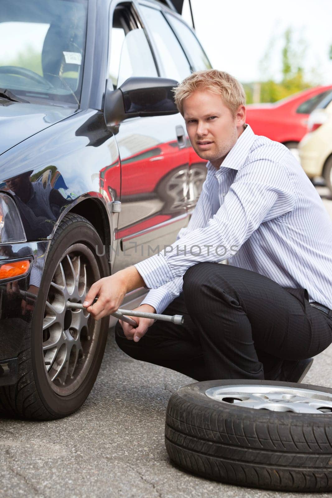 Unhappy business man replacing tire on car