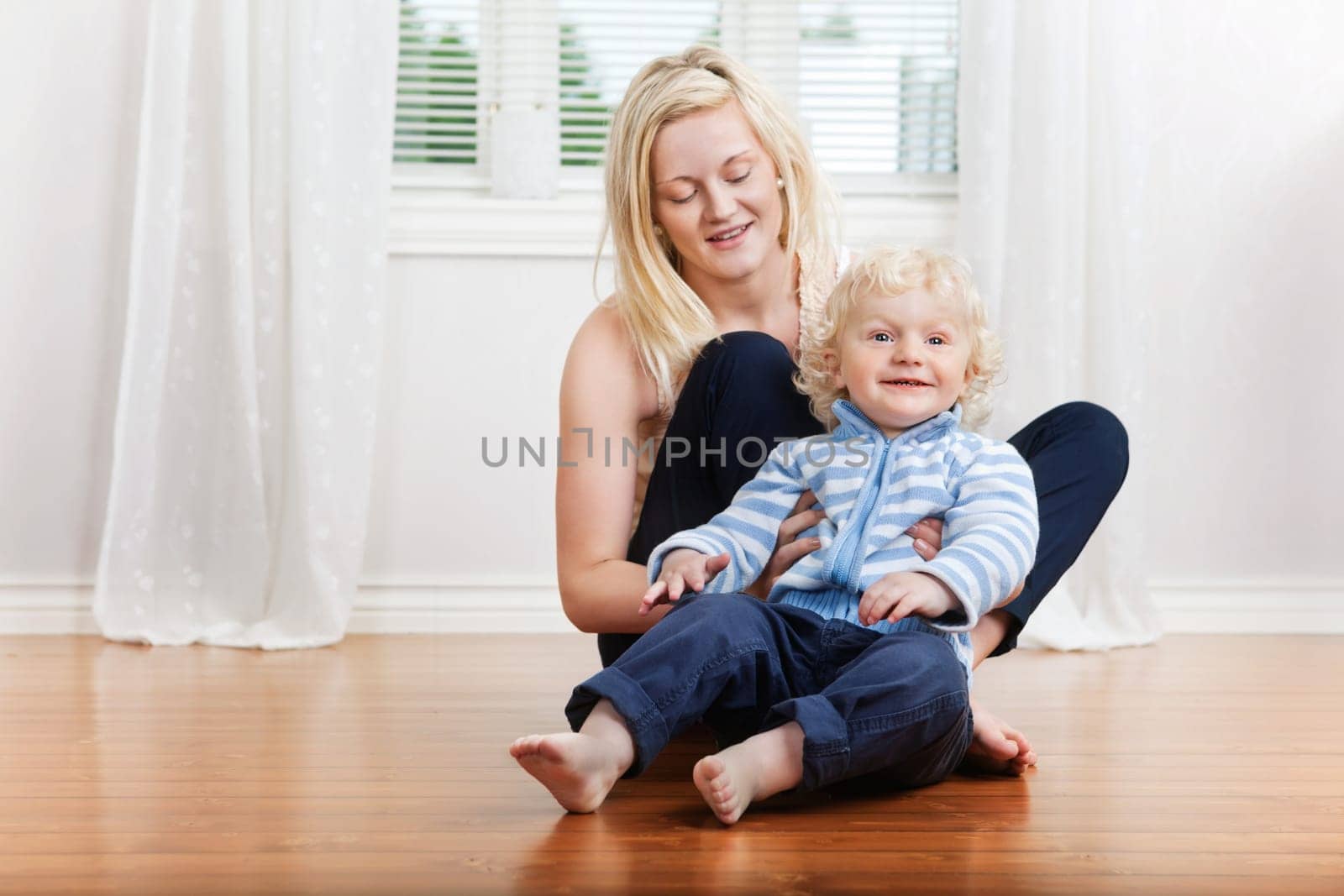 Smiling mother with cute little boy child sitting in house
