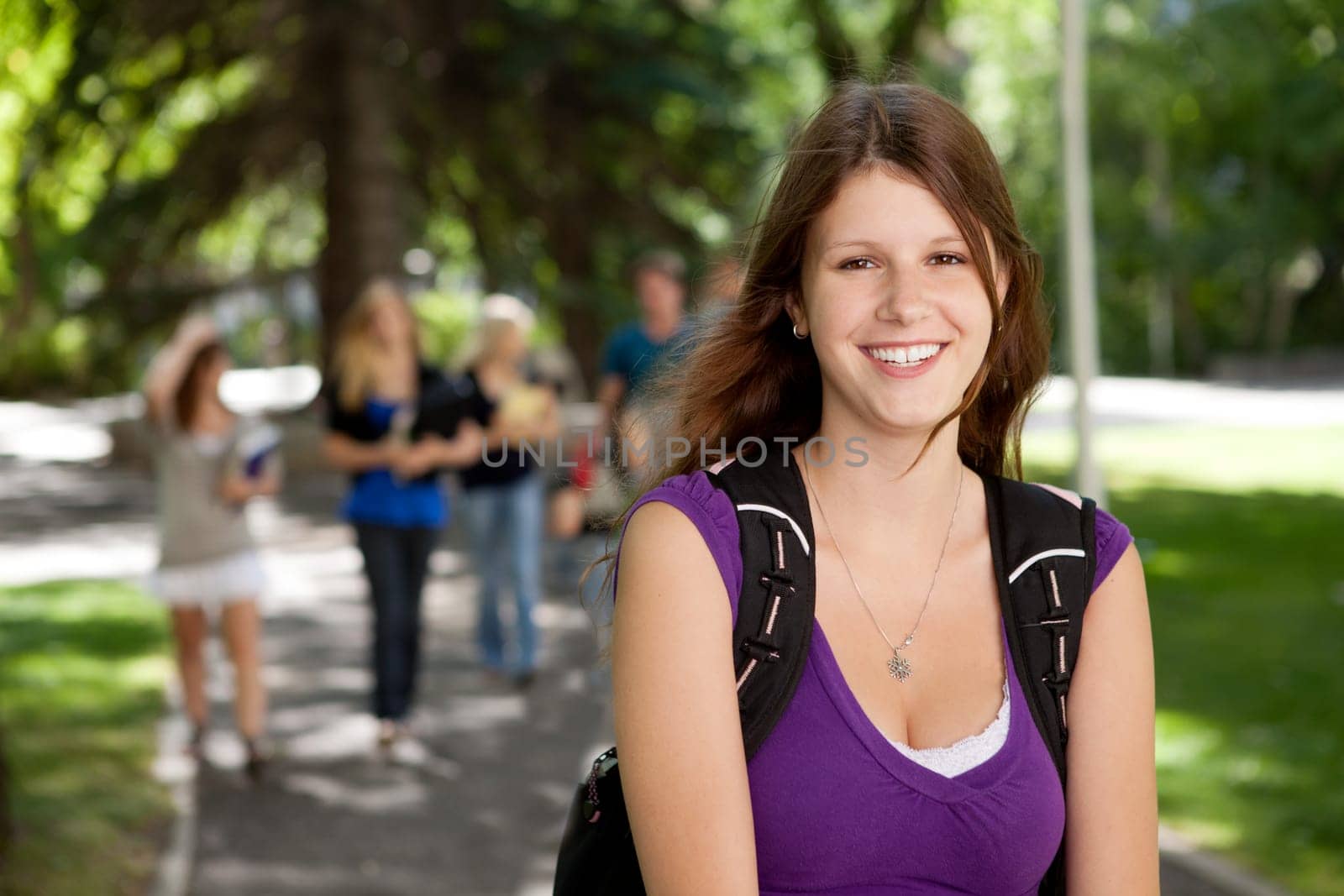 Portrait of a happy young college girl with friends in background
