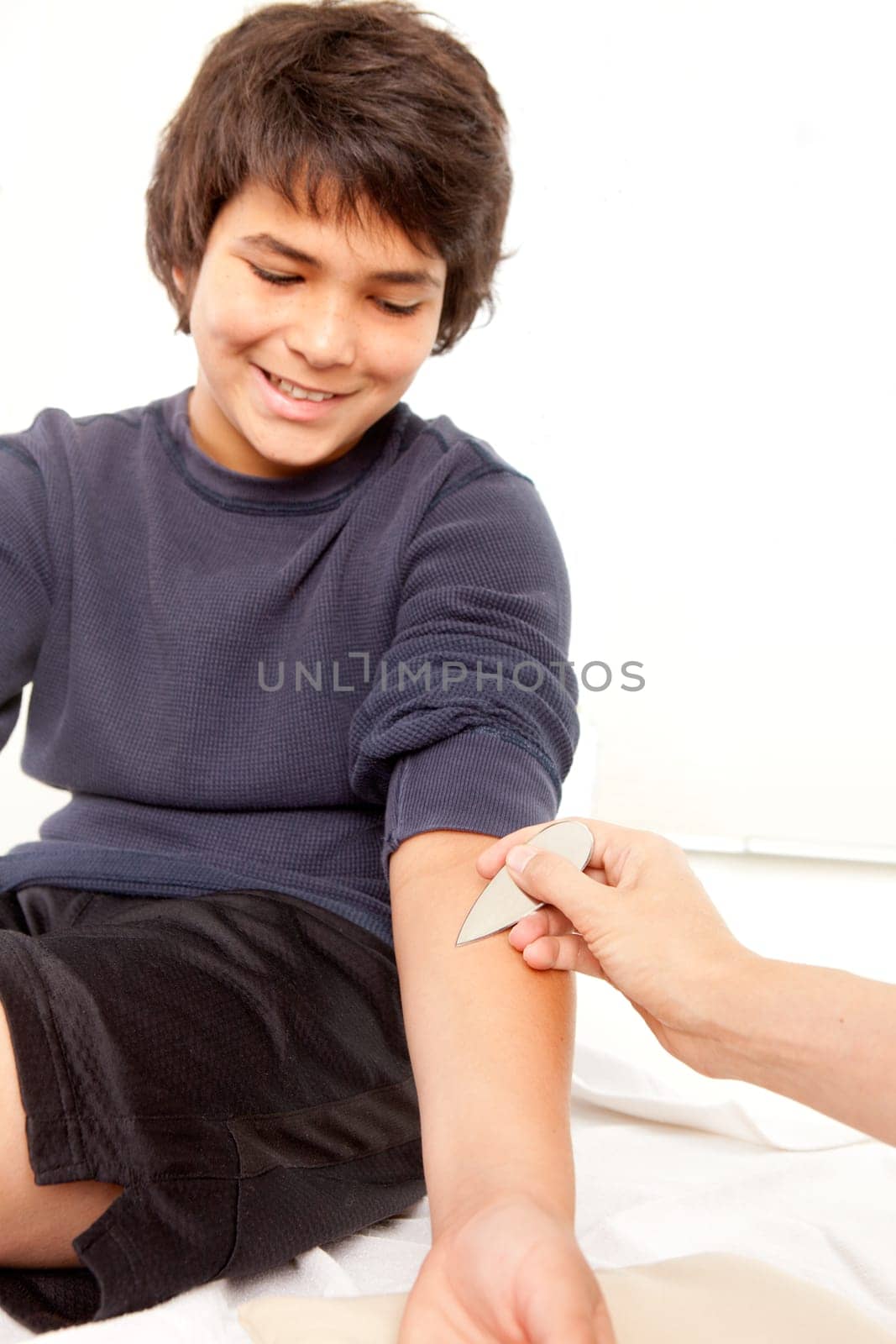 Chokishin acupuncture tool used in Shonishin treatment on a young male.  Shallow depth of field, focus on tool