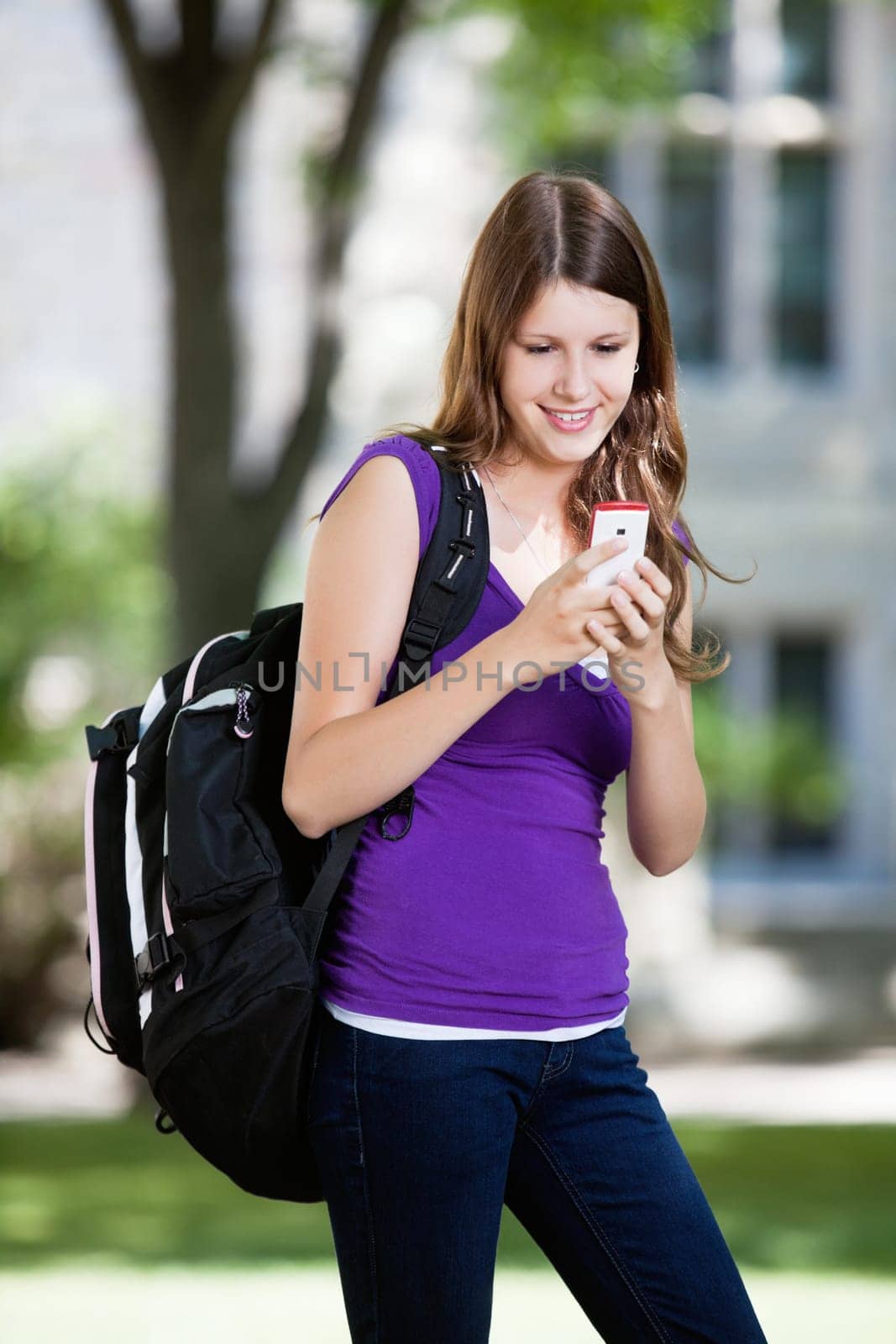 Pretty college girl busy texting on cell