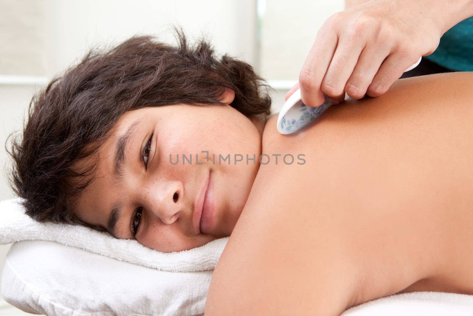 Portrait of young male receiving gua sha acupuncture treatment