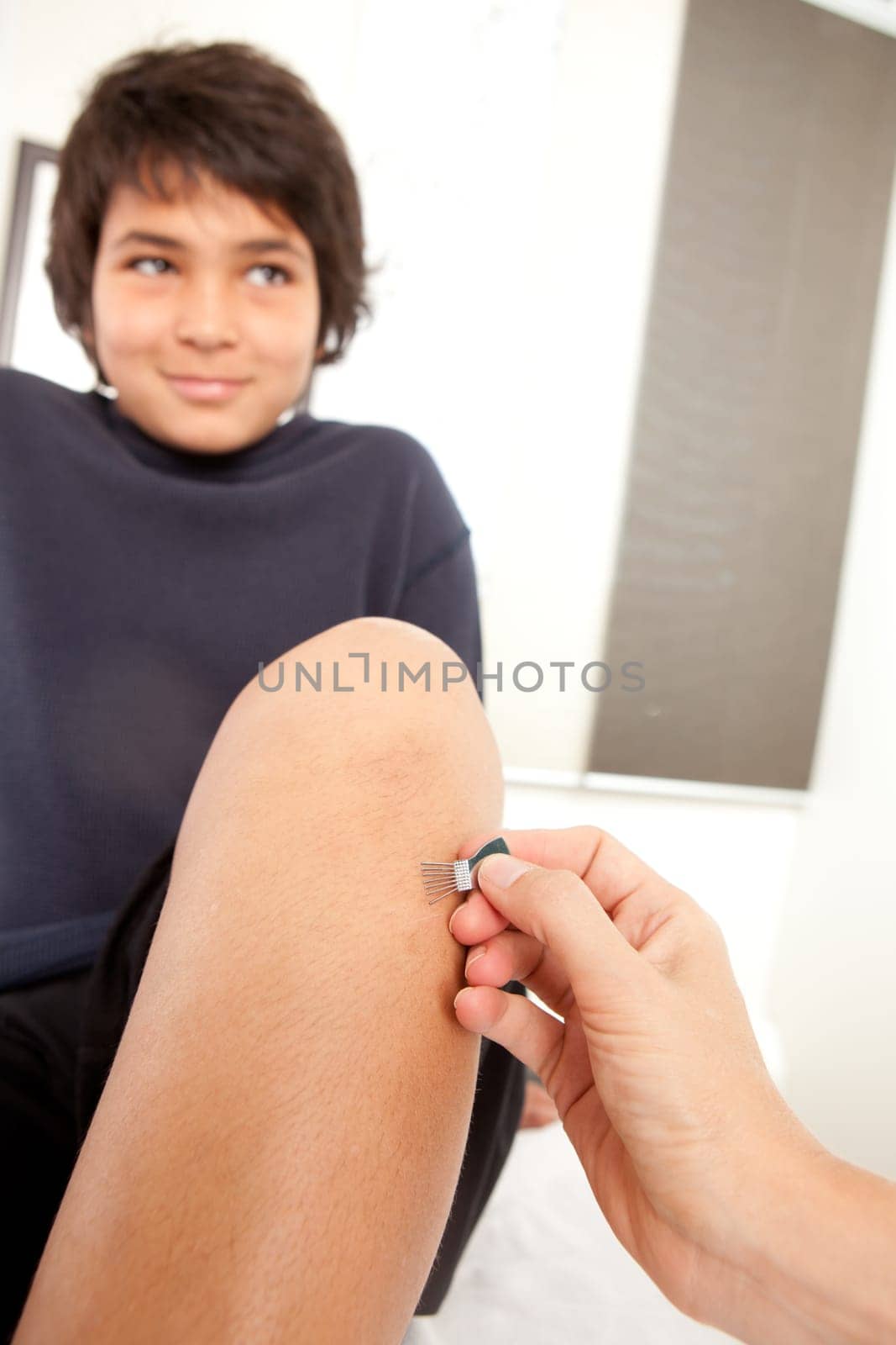 Young male receiving Japanese Shonishin acupuncture on leg with a pine brush tool