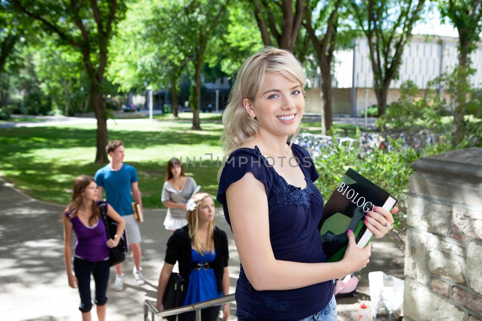 Portrait of sweet young girl going to college with friends in background