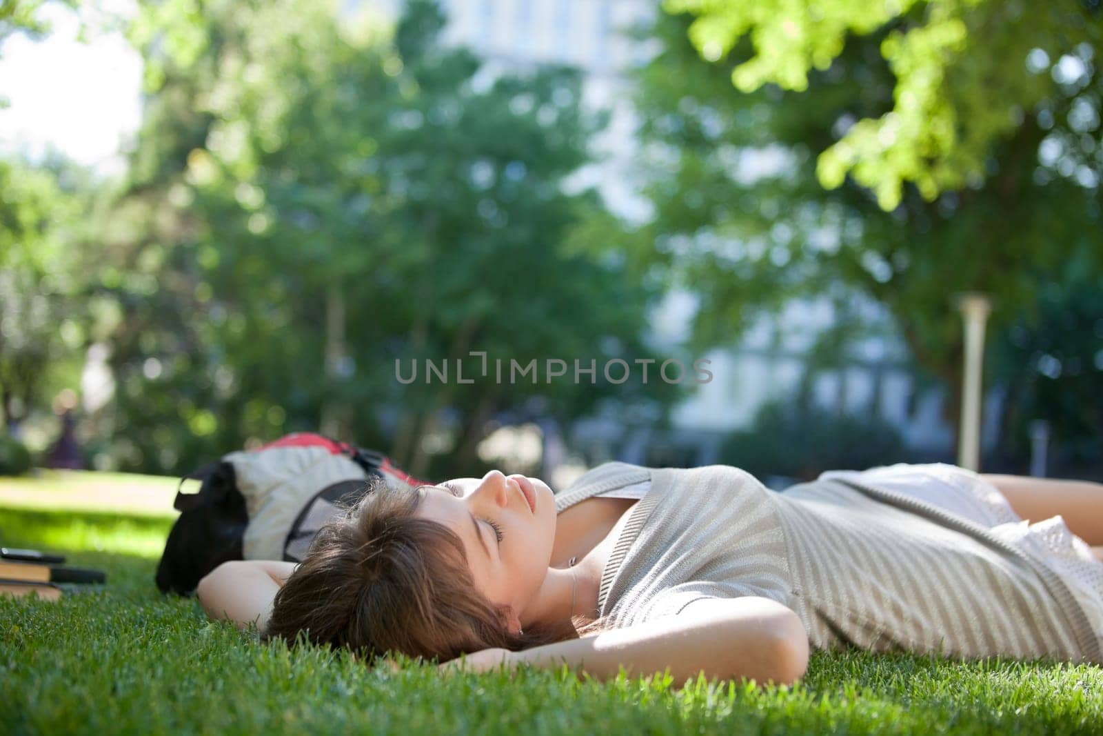 Young college student lying down on grass at campus lawn