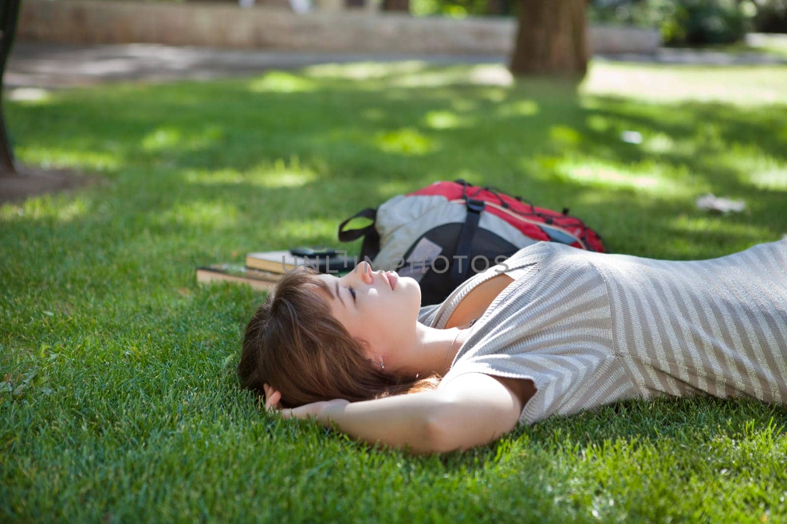 Young college student lying down on grass at campus lawn