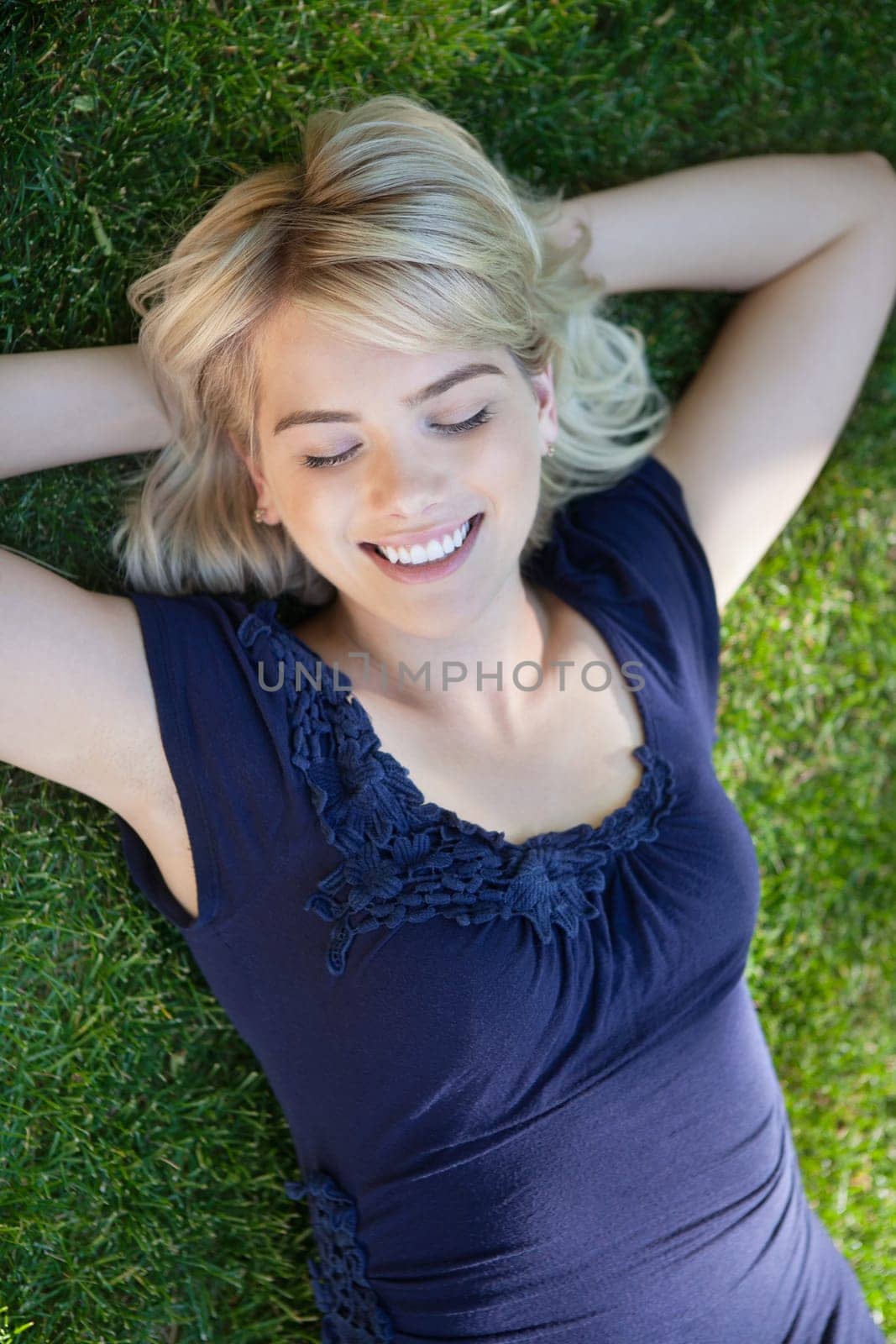 Smiling young woman lying on grass with eyes closed