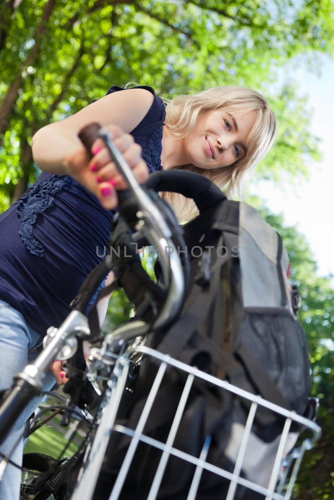 Low angle view of cute female student standing with her bike