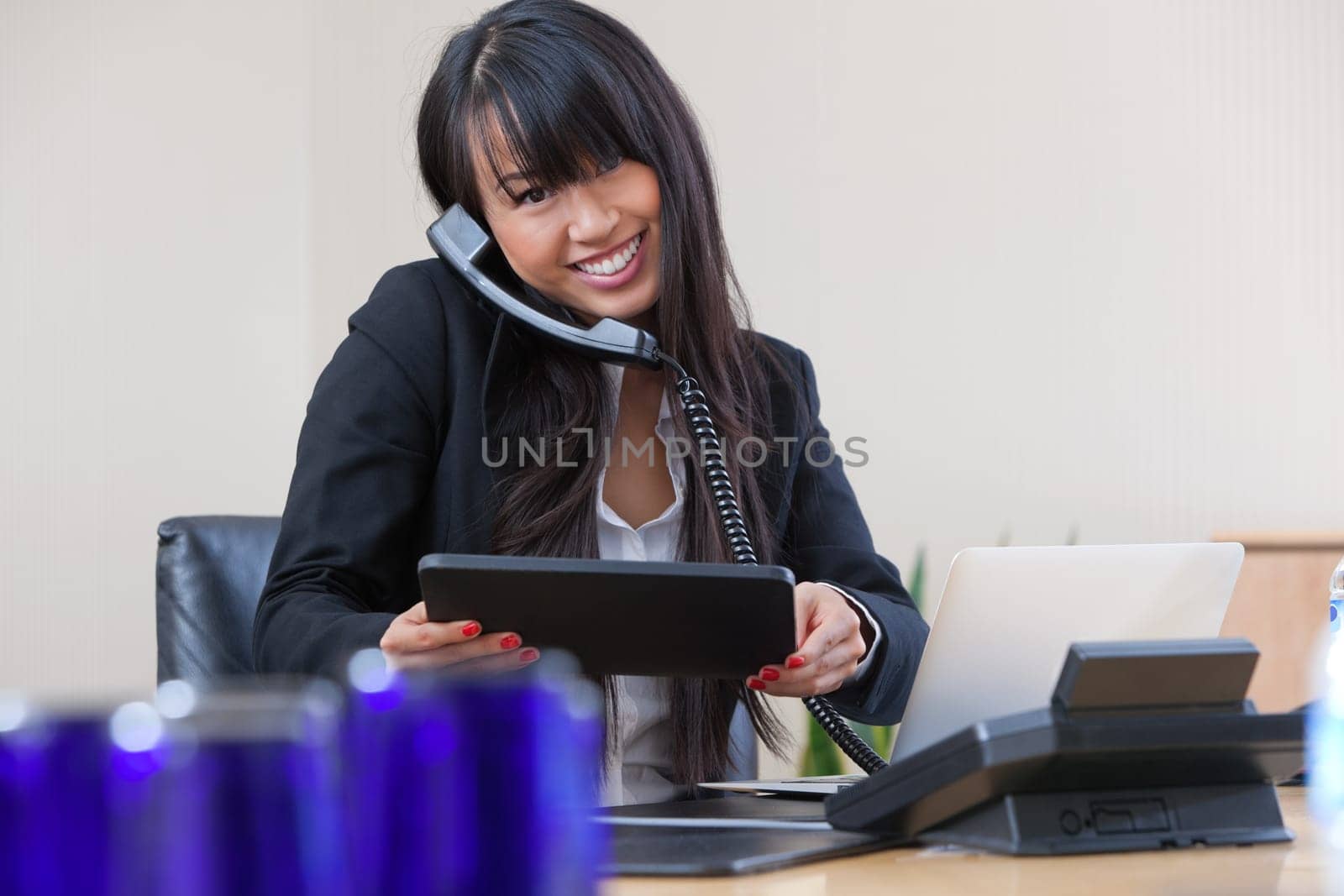 Portrait of young smiling businesswoman having conversation on landline phone