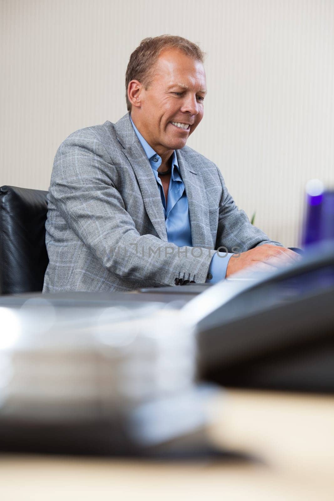 Cheerful businessman working on laptop at office