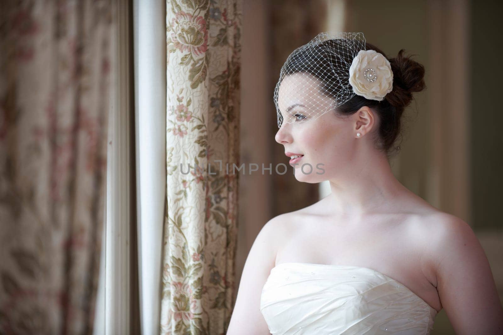 Pretty bride looking out of window and smiling on her wedding day