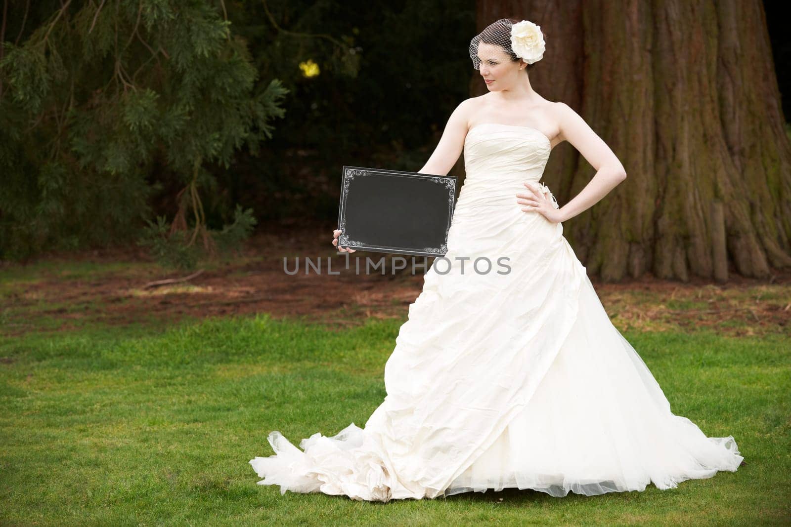 Pretty bride in wedding dress holding a blank board with space for copy