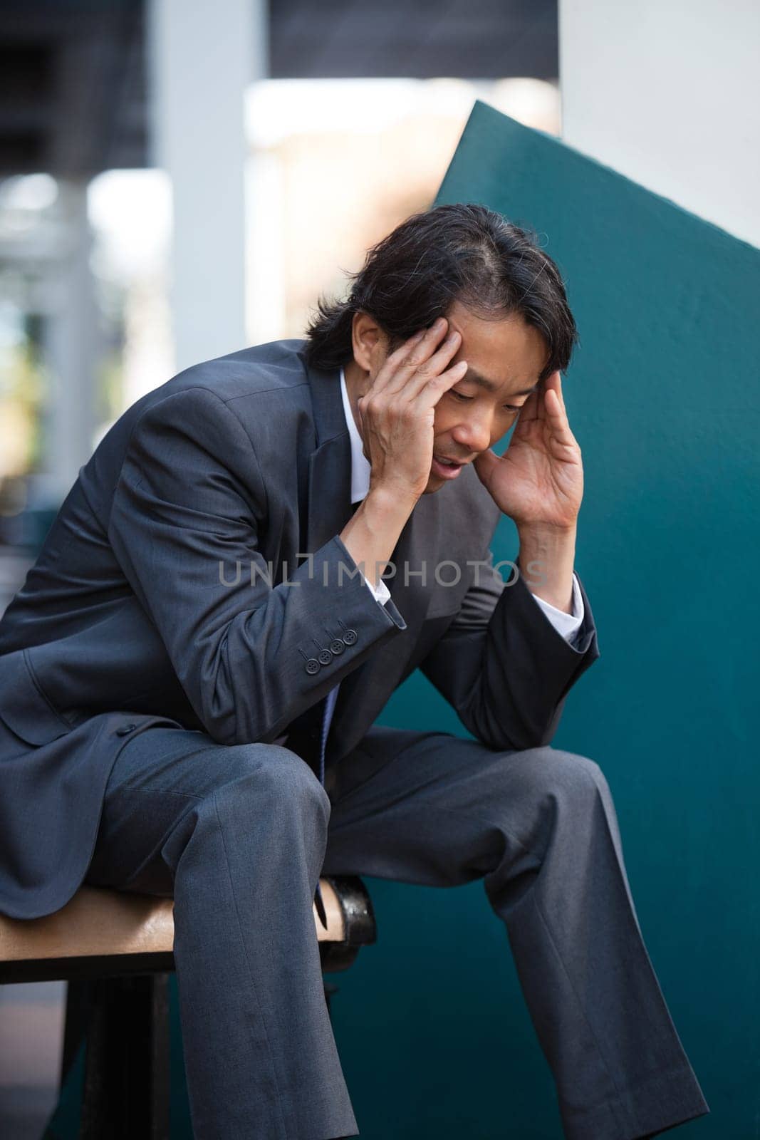 Business man sitting on bench outdoors not feeling well