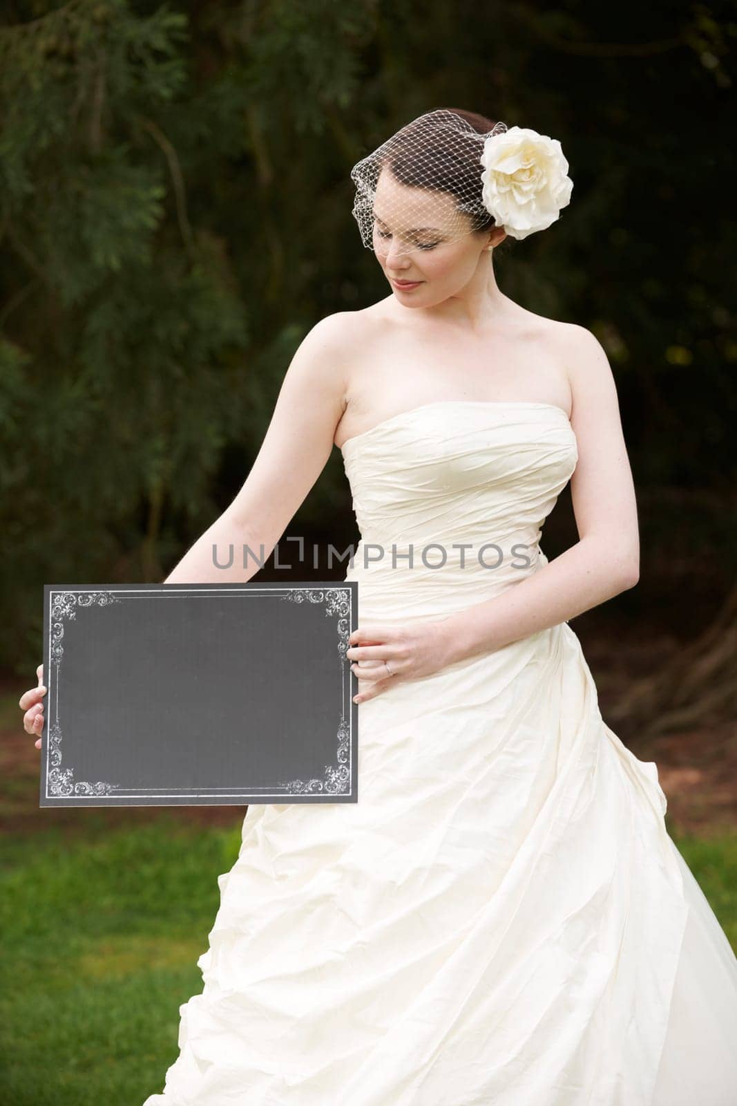 Pretty bride in wedding dress holding a blank board with space for copy