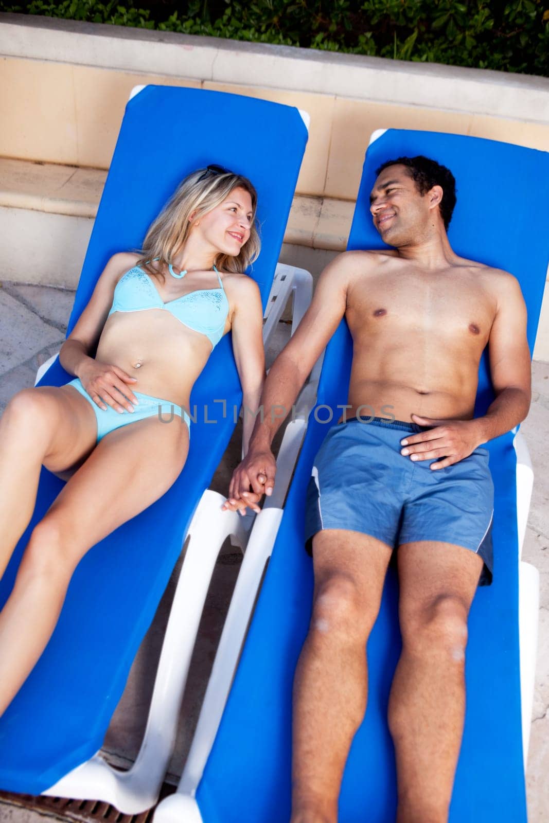 A happy couple lounging in pool chairs