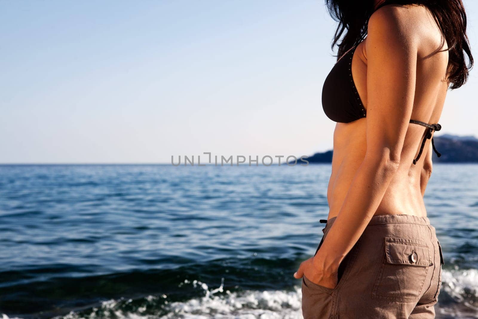 A woman standing on the beach looking out at the horizon