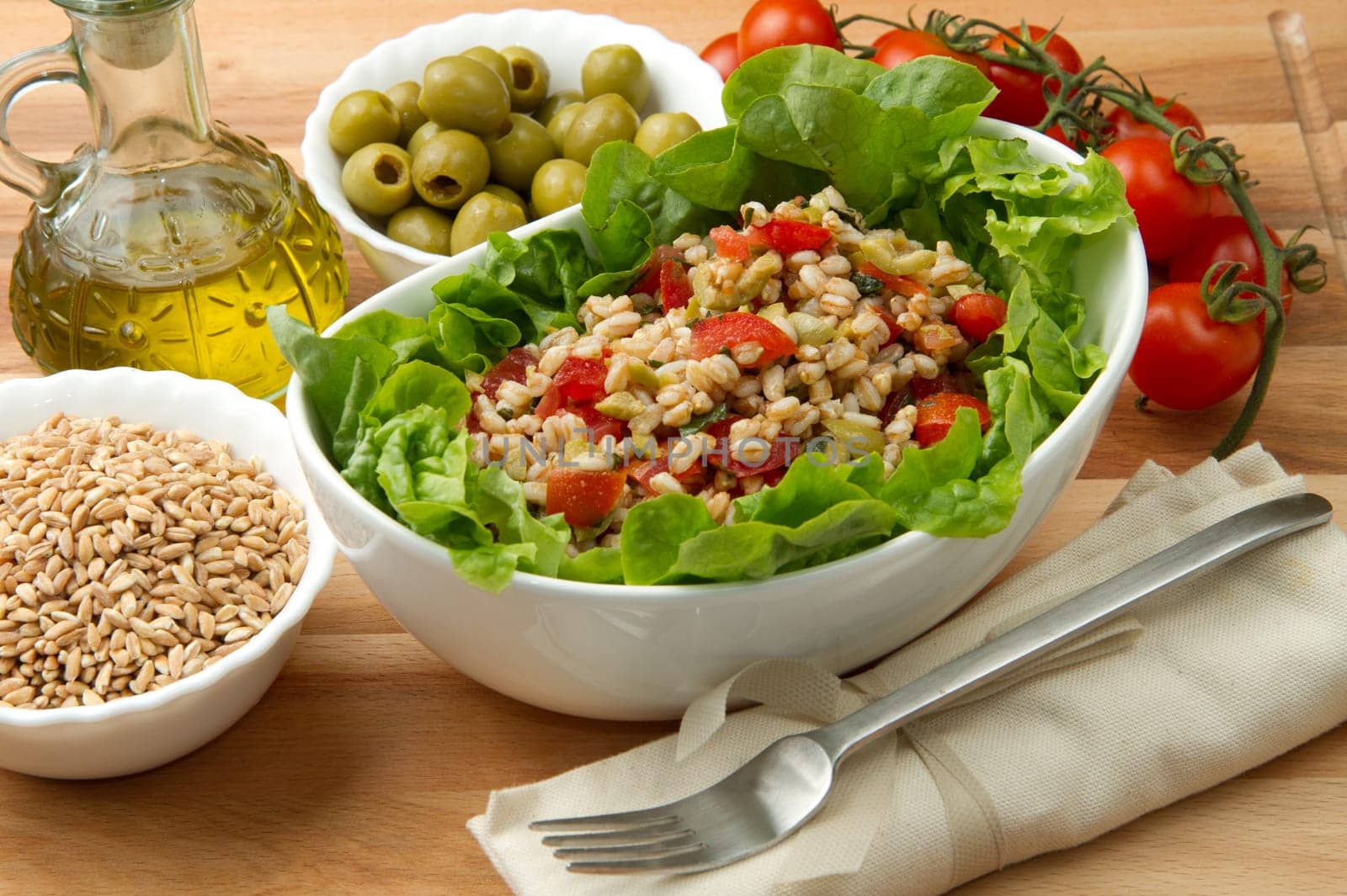 a dish with spelt salad with tomatoes,olive and salad