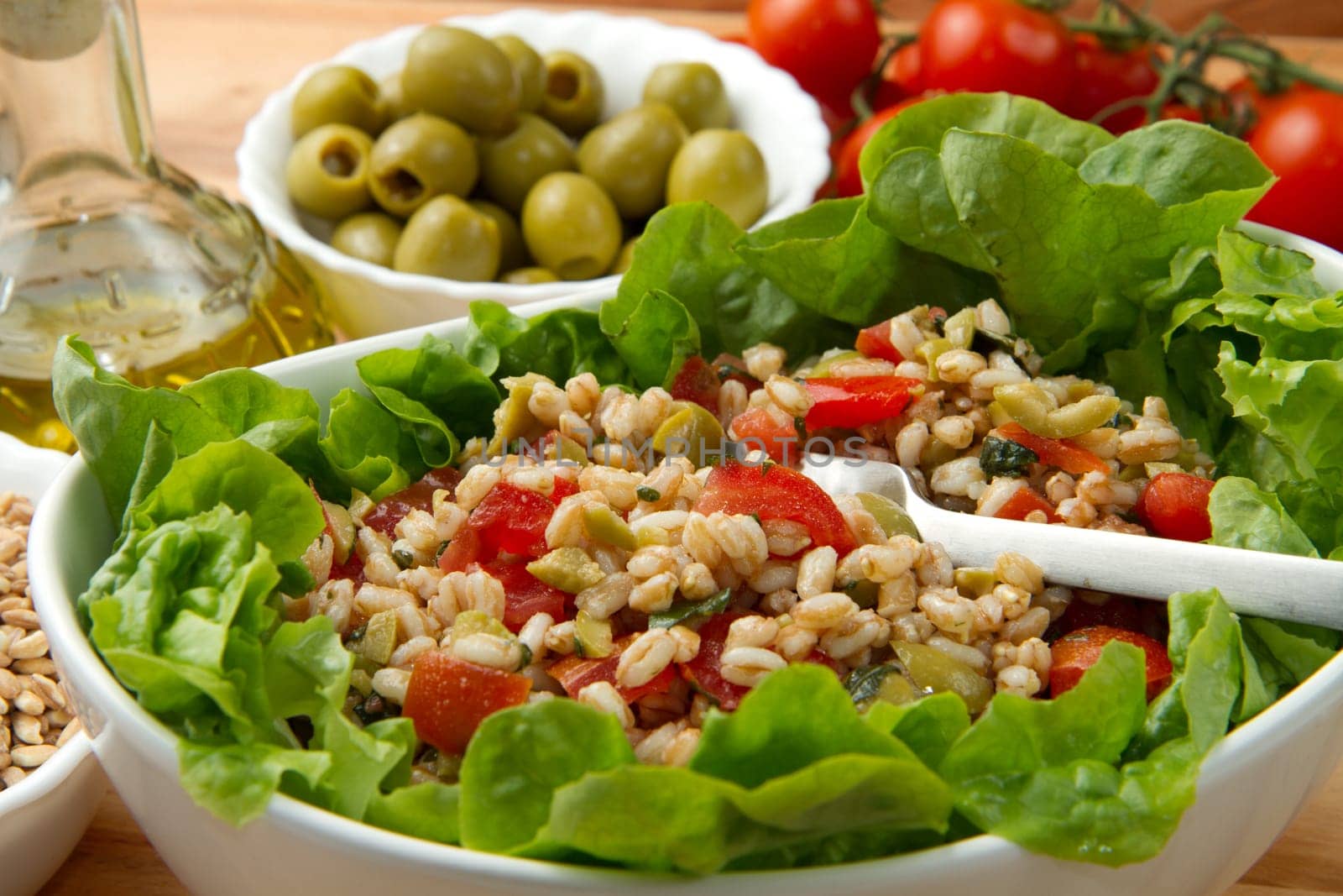 a dish with spelt salad with tomatoes,olive and salad