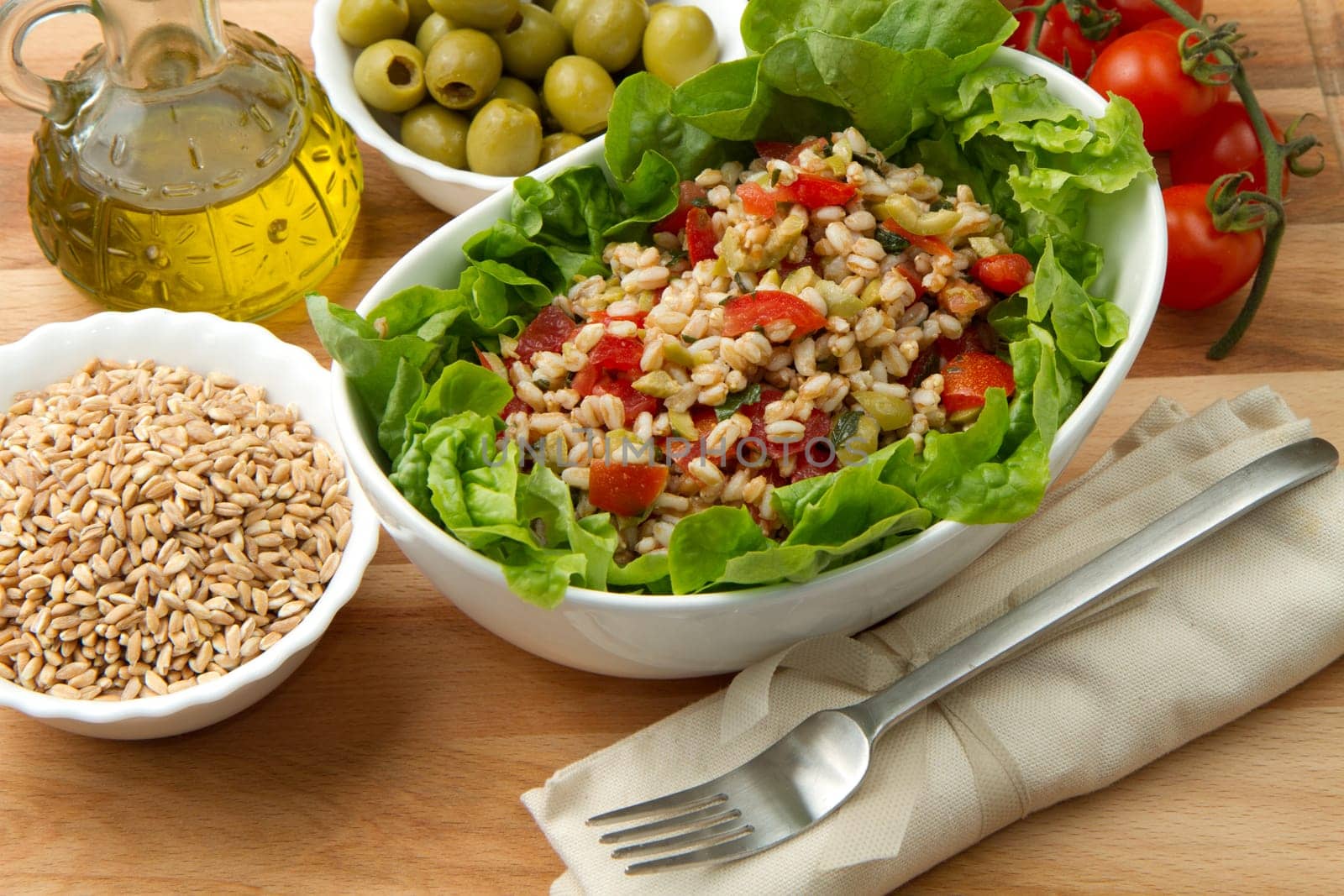 a dish with spelt salad with tomatoes,olive and salad