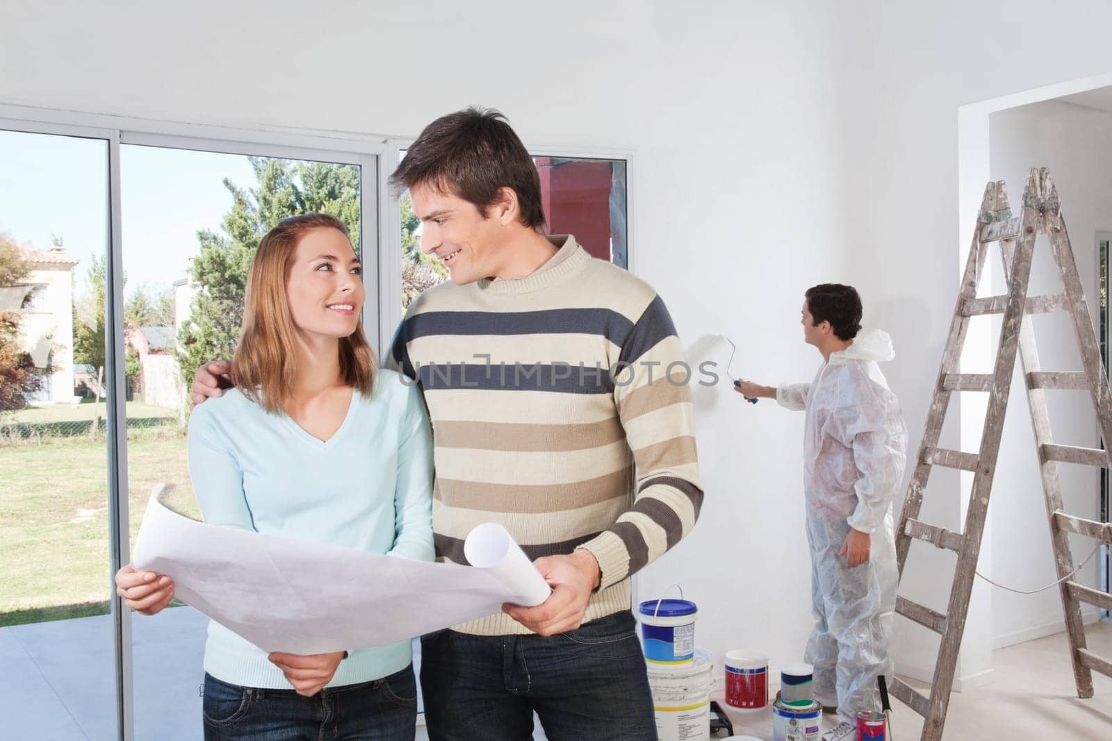 Young couple looking at each other with painter in background