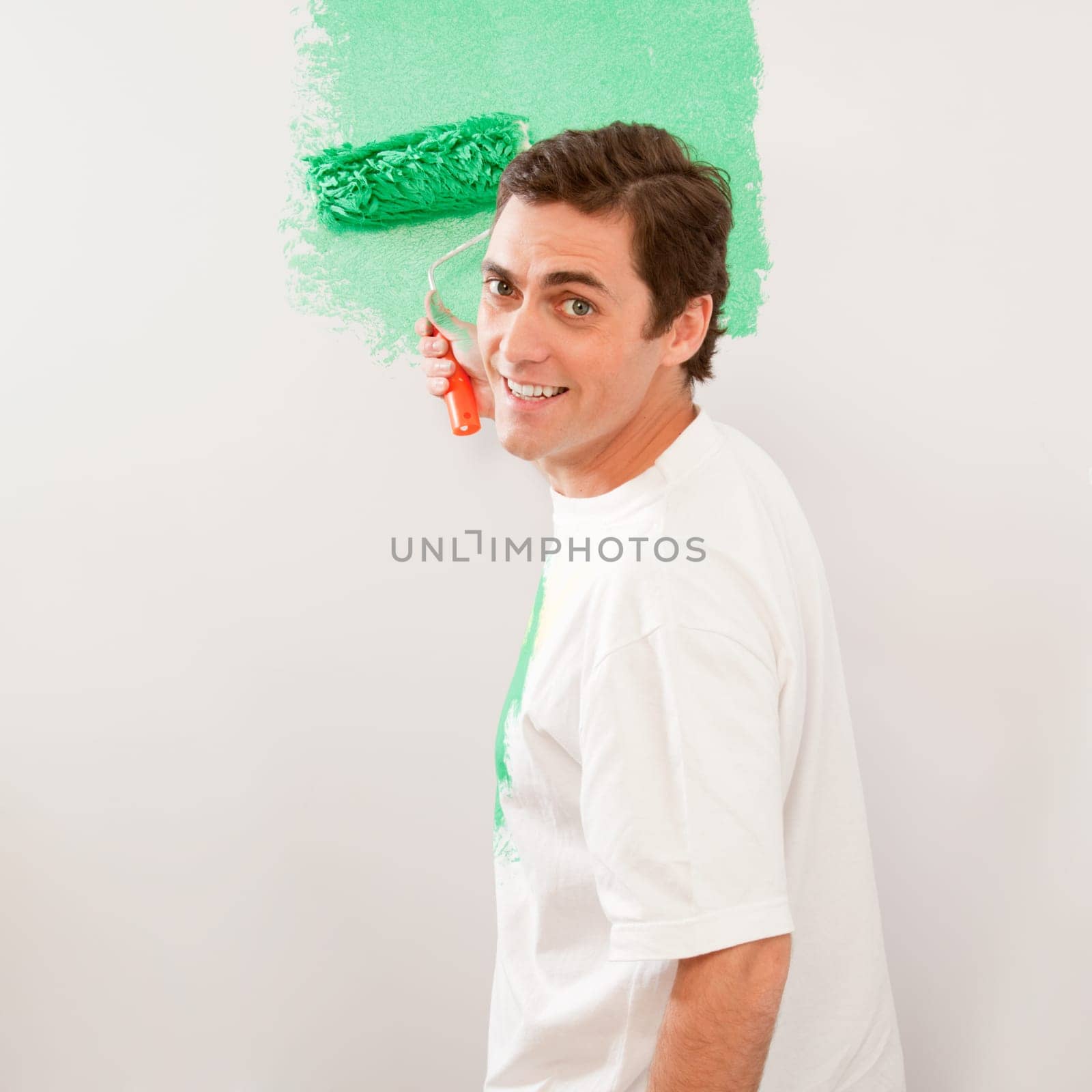 A man paiting a wall with a roller brush