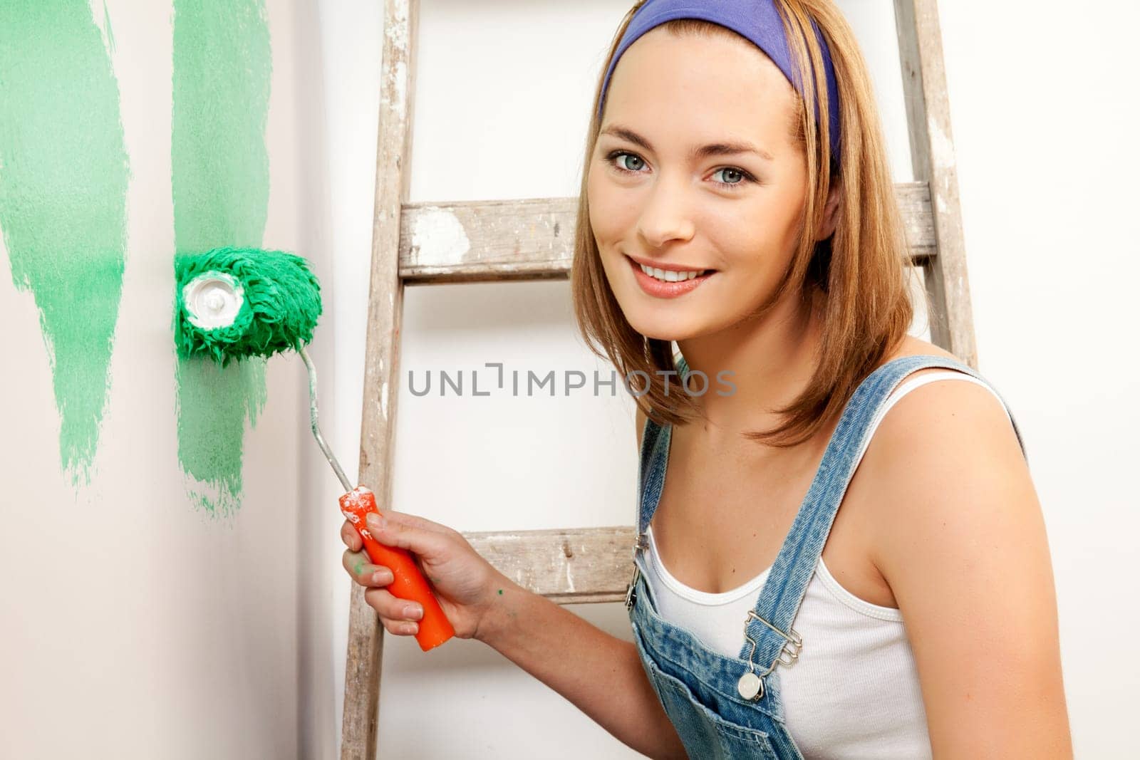 A woman with a roller brush, paiting the wall doing home improvements