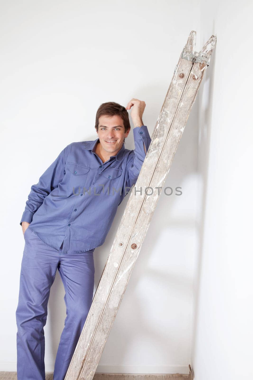 Young man leaning on wooden ladder and smiling