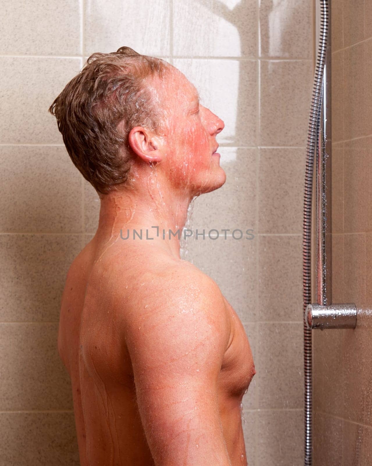 A man standing in a shower with water on face