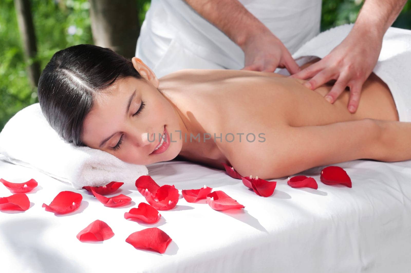 Beautiful woman getting massage and spa treatment in natural setting