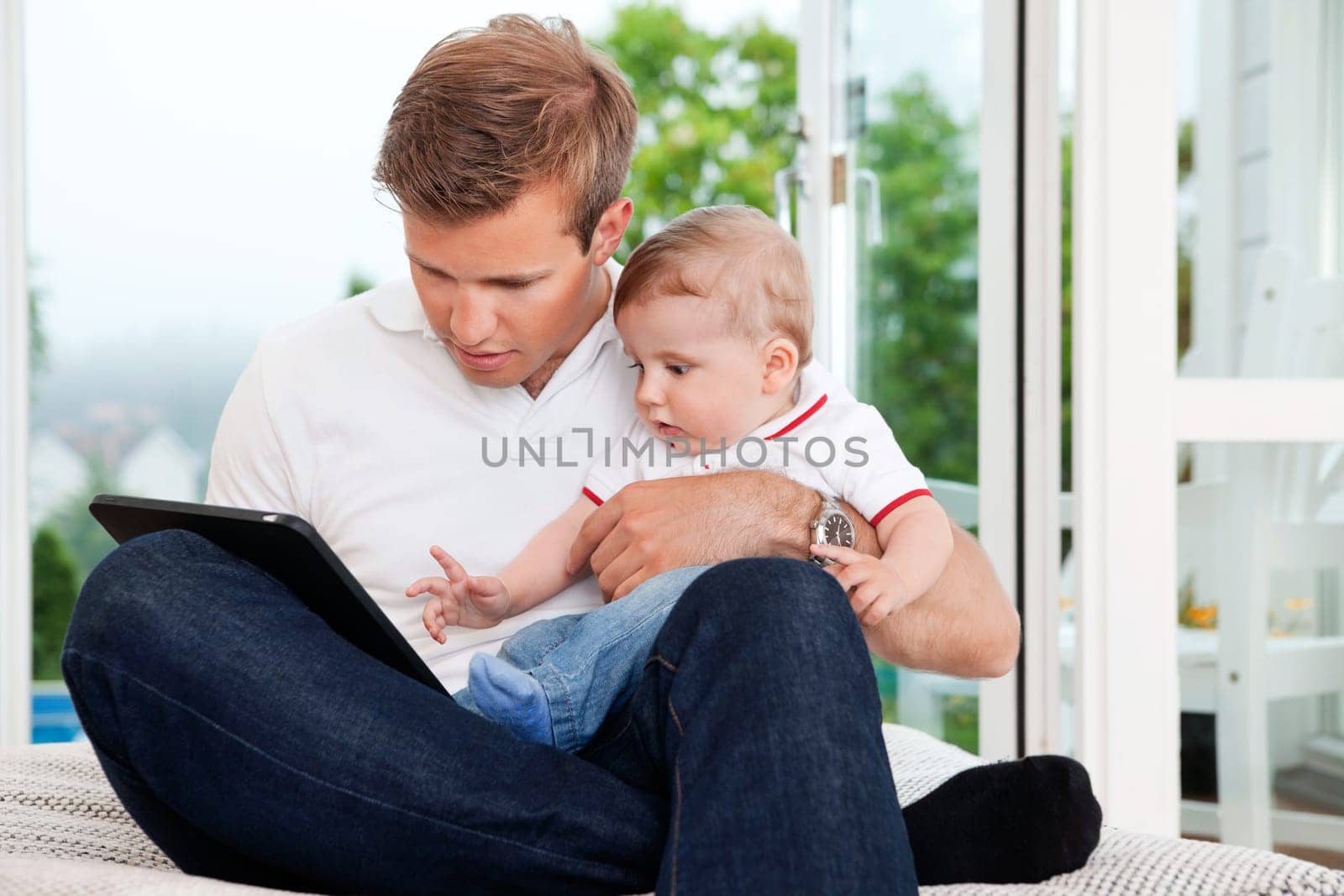 Father holding child while using digital tablet at home