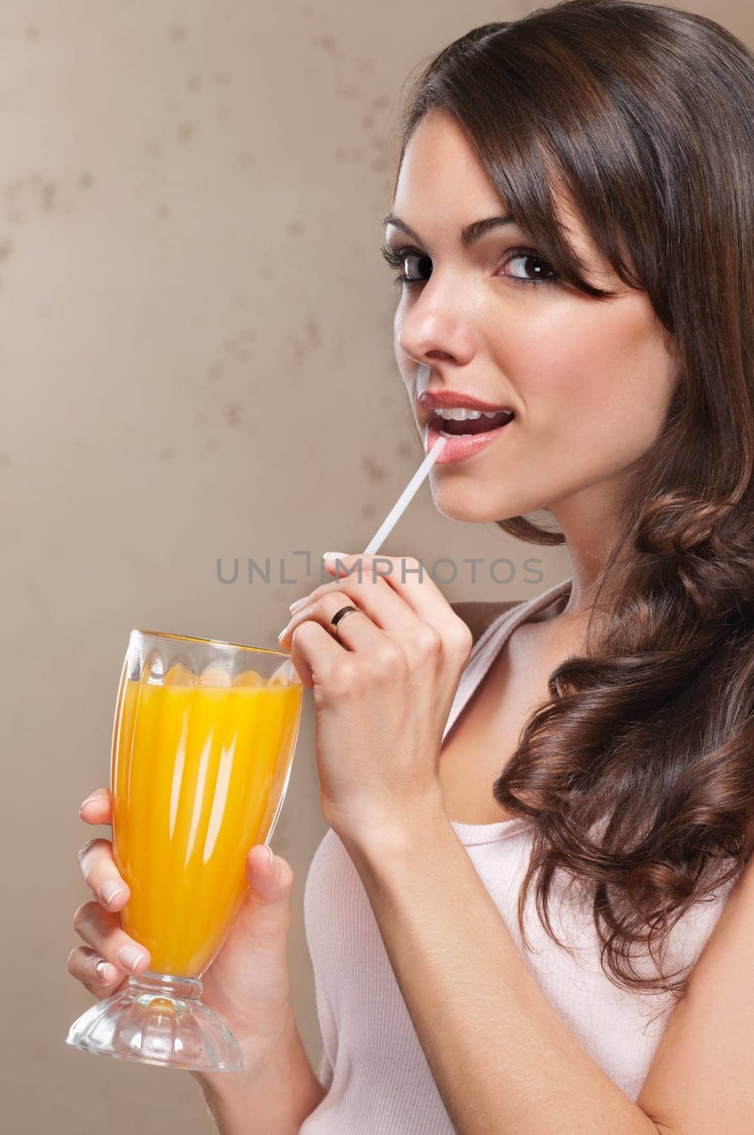 Close-up portrait of beautiful woman drinking orange juice with straw
