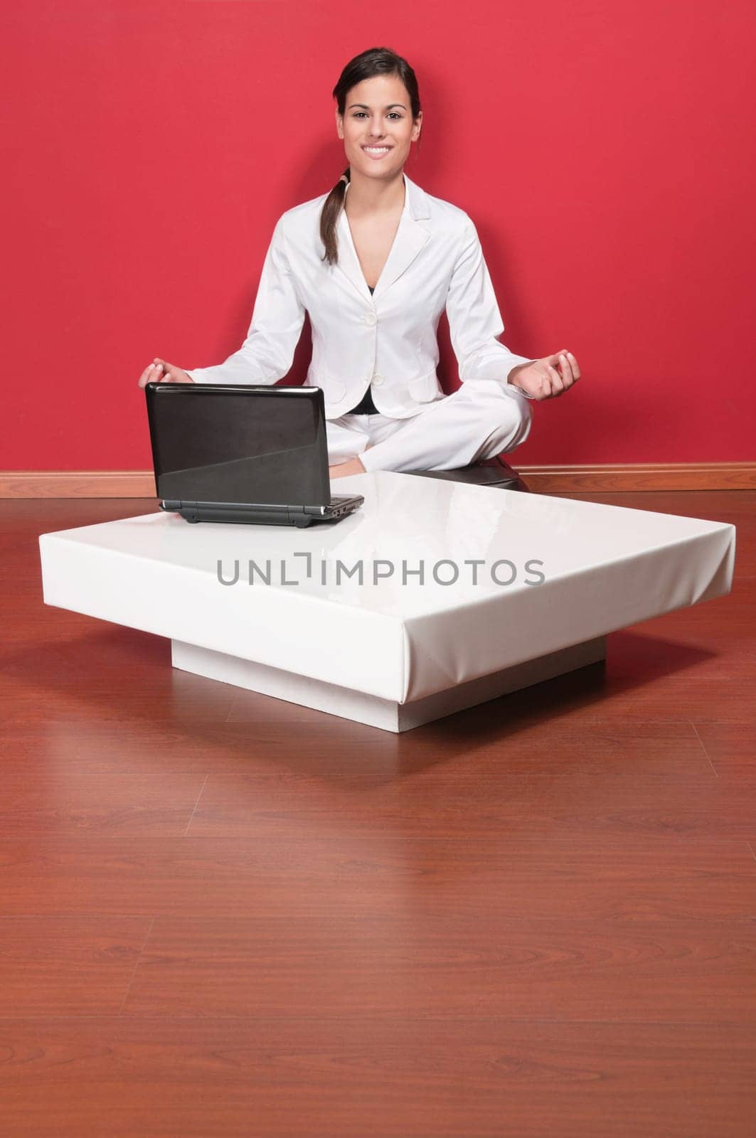 Young beautiful businesswoman sitting in yoga lotus position with laptop on table