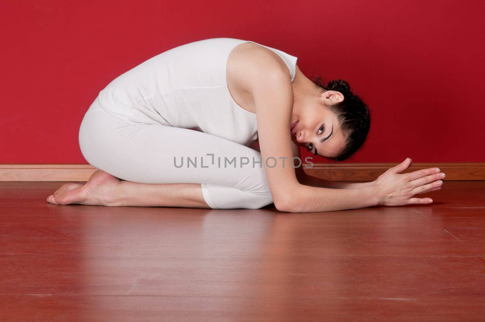 Pretty young woman in a exercise clothing in a yoga pose on floor