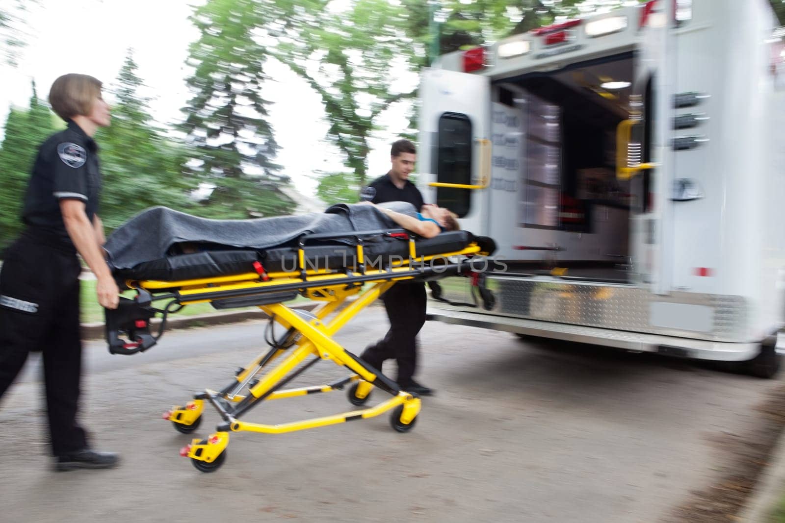 Emergency workers rushing senior woman into an ambulance