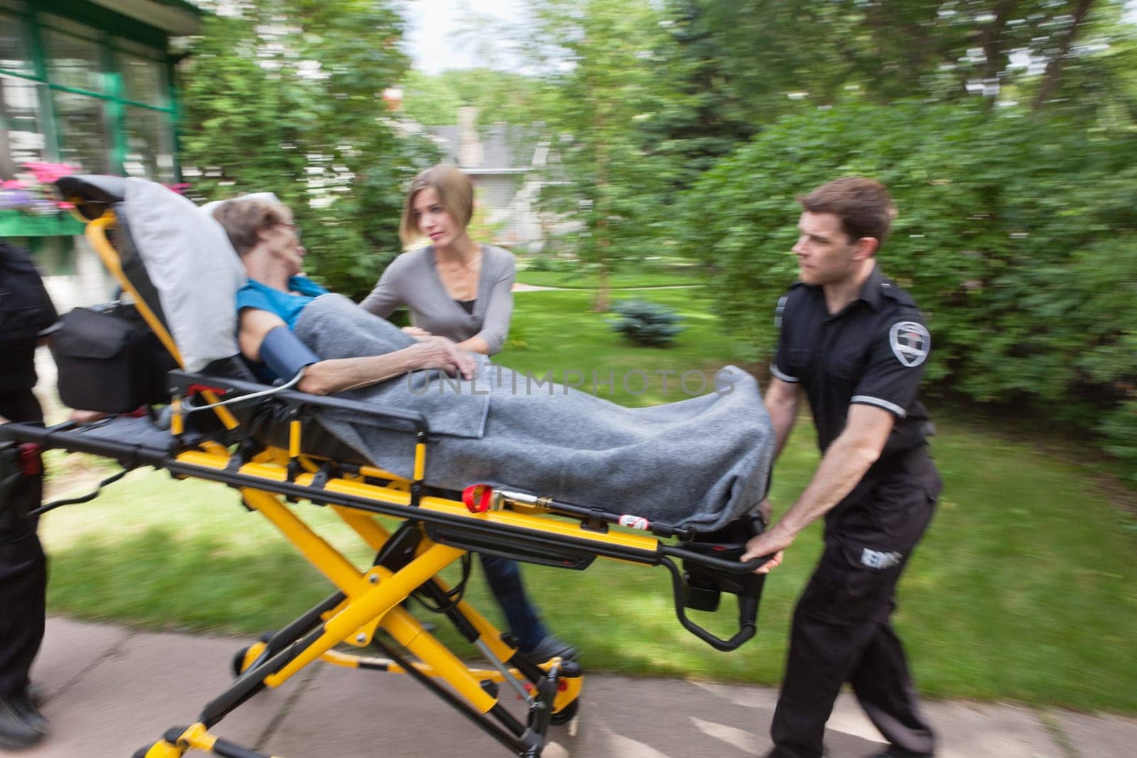 Senior woman being rushed to hospital on ambulance stretcher