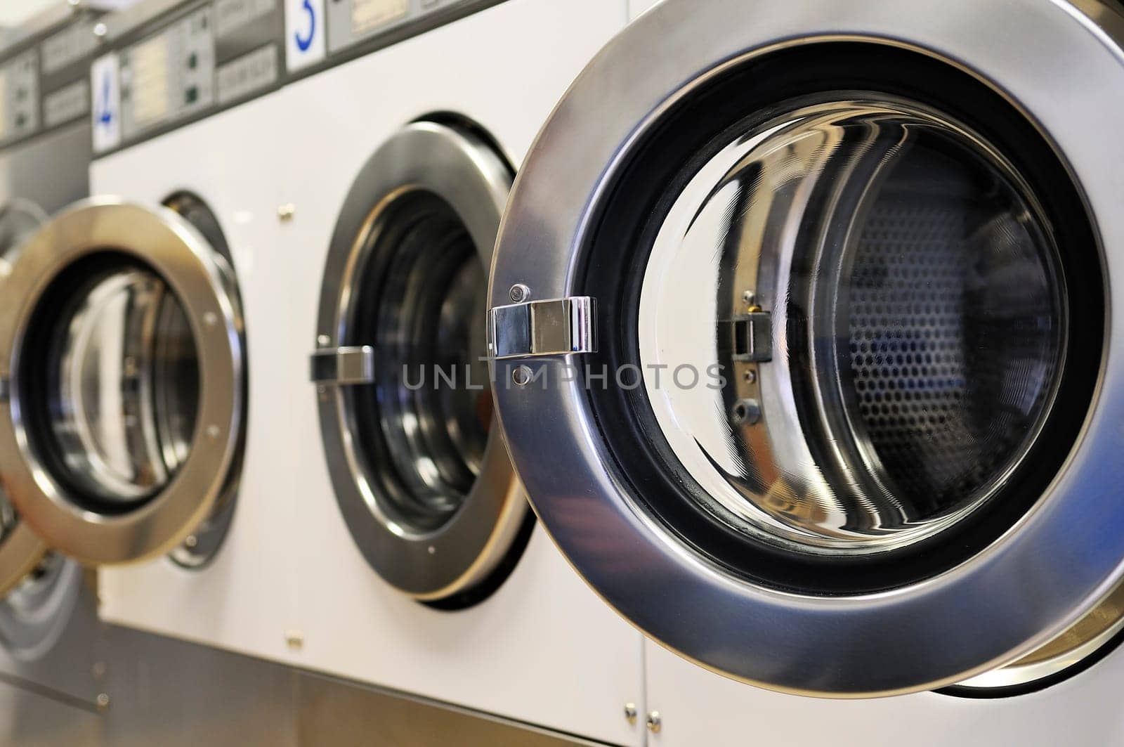 A row of industrial washing machines in a public laundromat