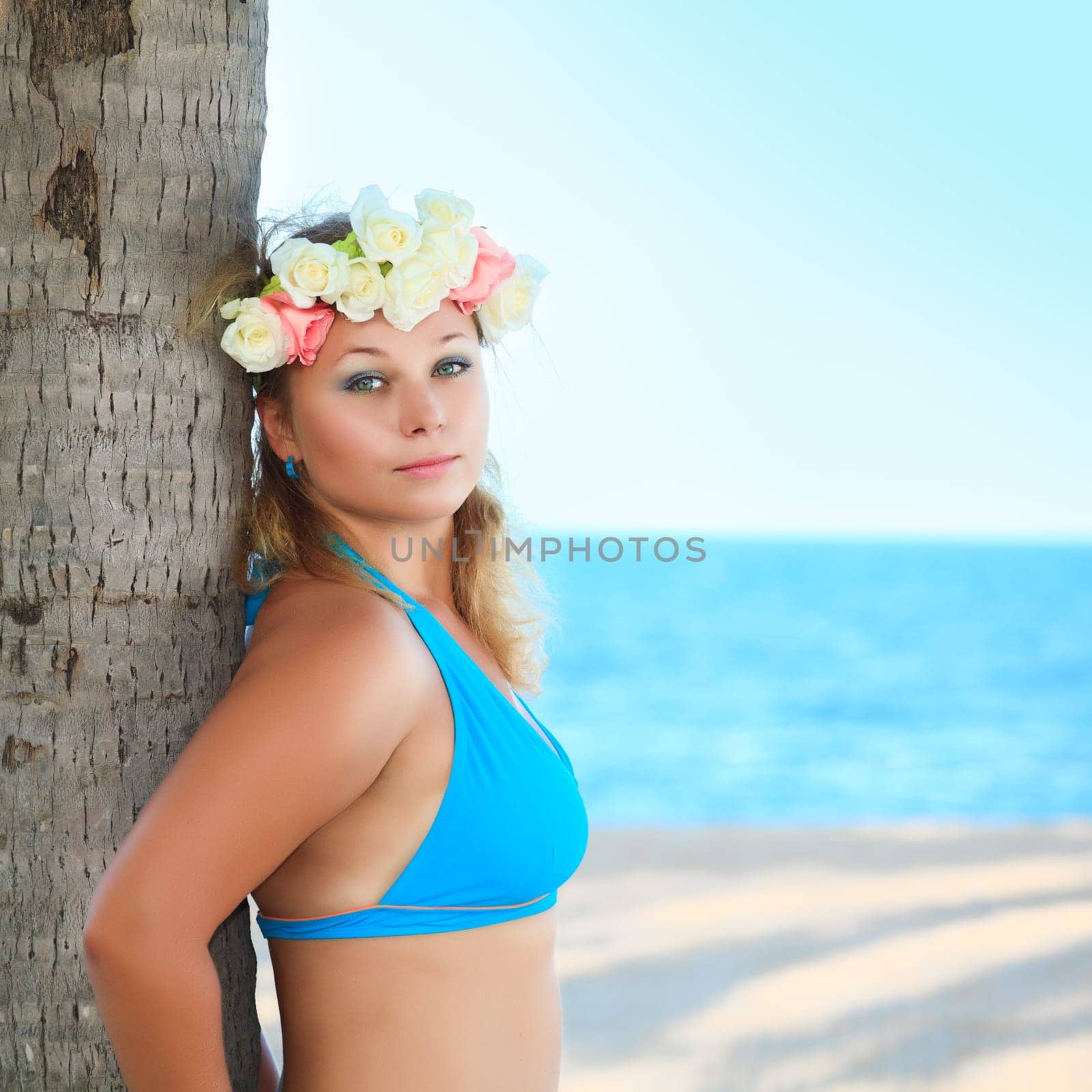 Beautiful woman near the trunk of palm tree
