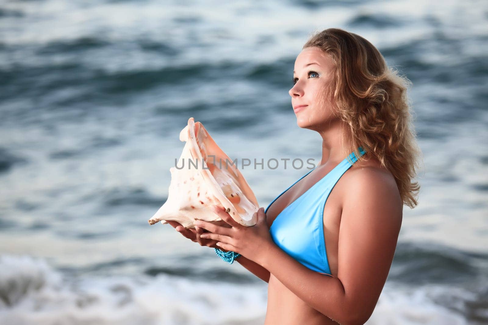 Young beautiful woman with seashell in her hands