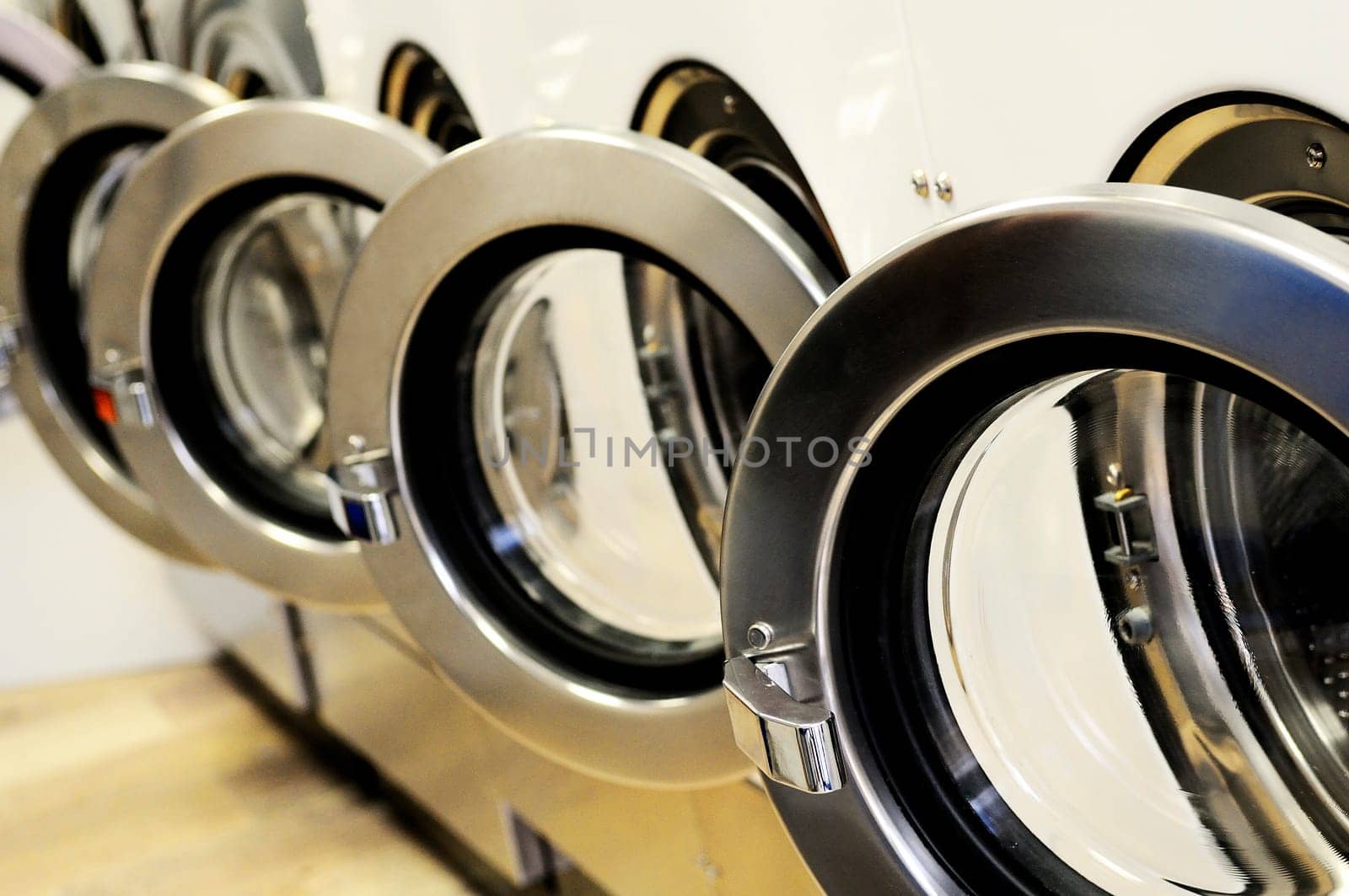 A row of industrial washing machines in a public laundromat